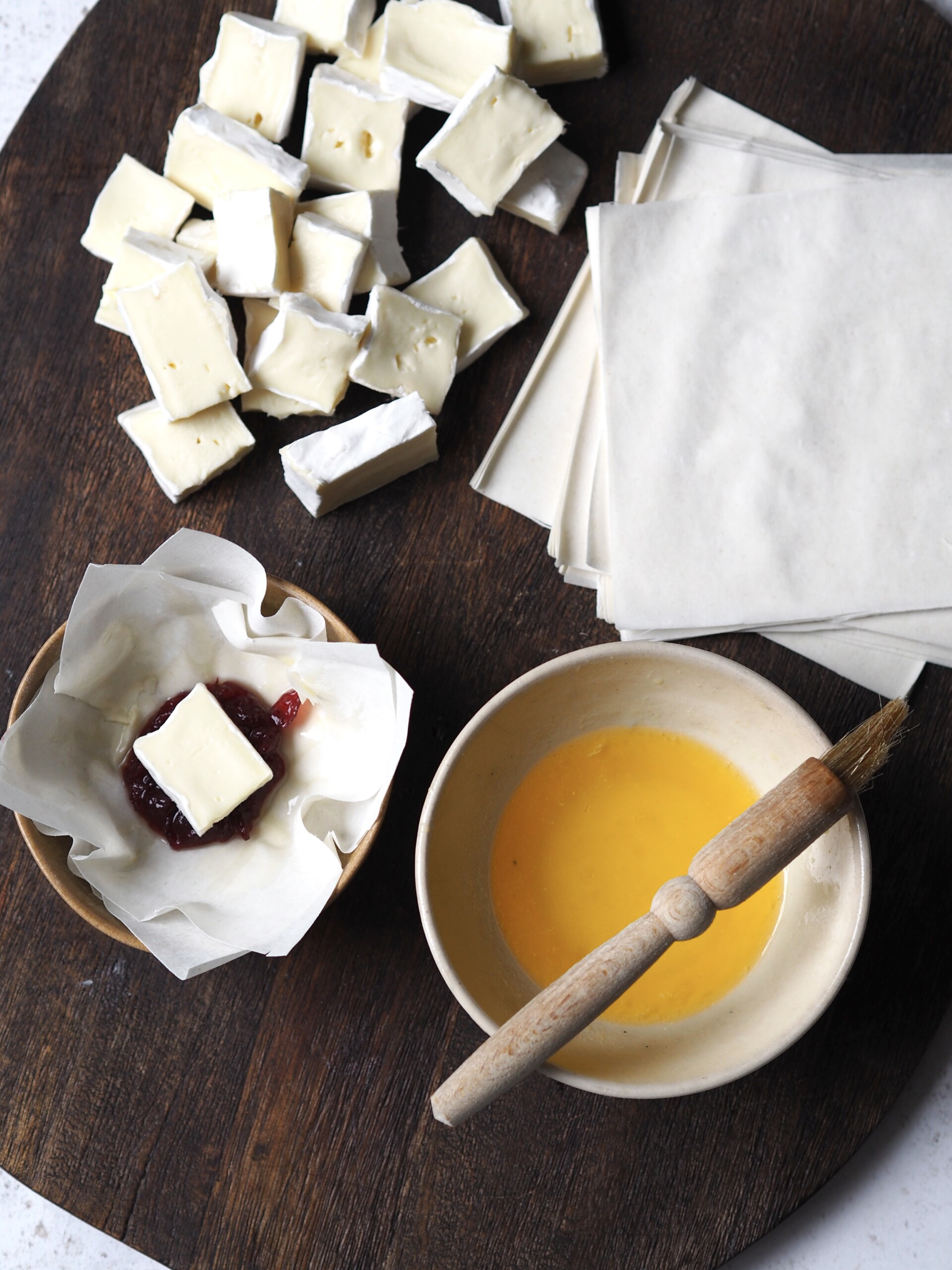 Brie and cranberry filo parcels being assembled on a wooden board.