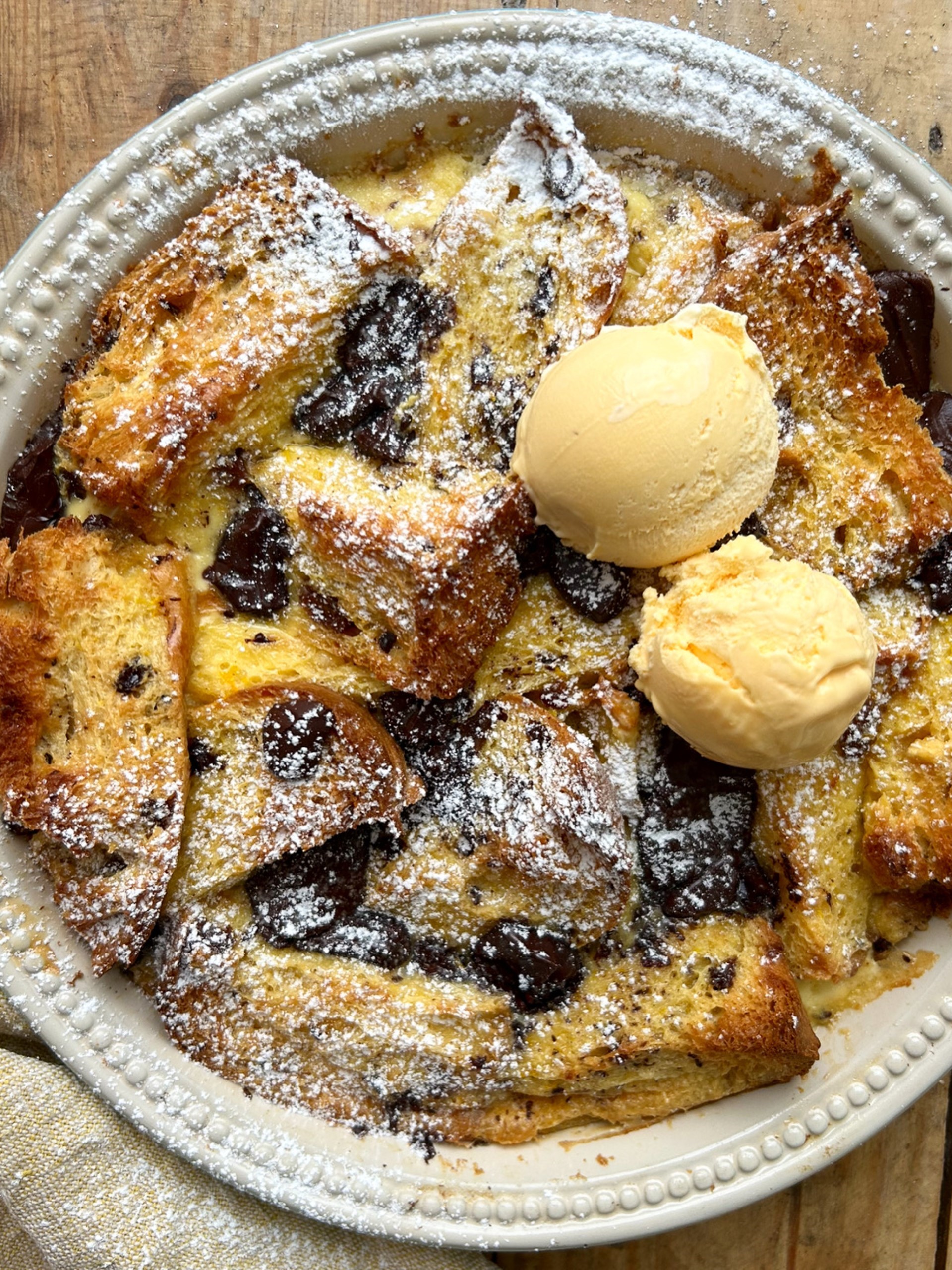 Panettone, Orange and Dark Chocolate Bread and Butter Pudding in a dish topped with ice cream