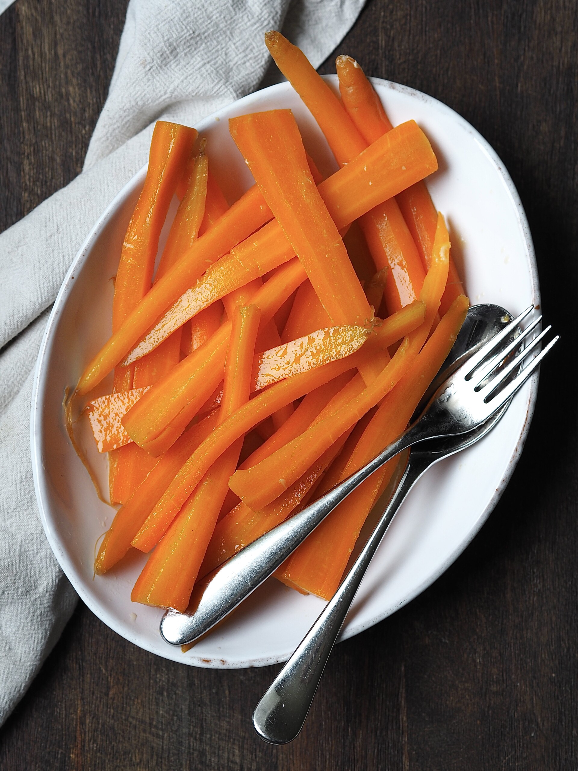 Maple and butter glazed carrots in a white serving dish.