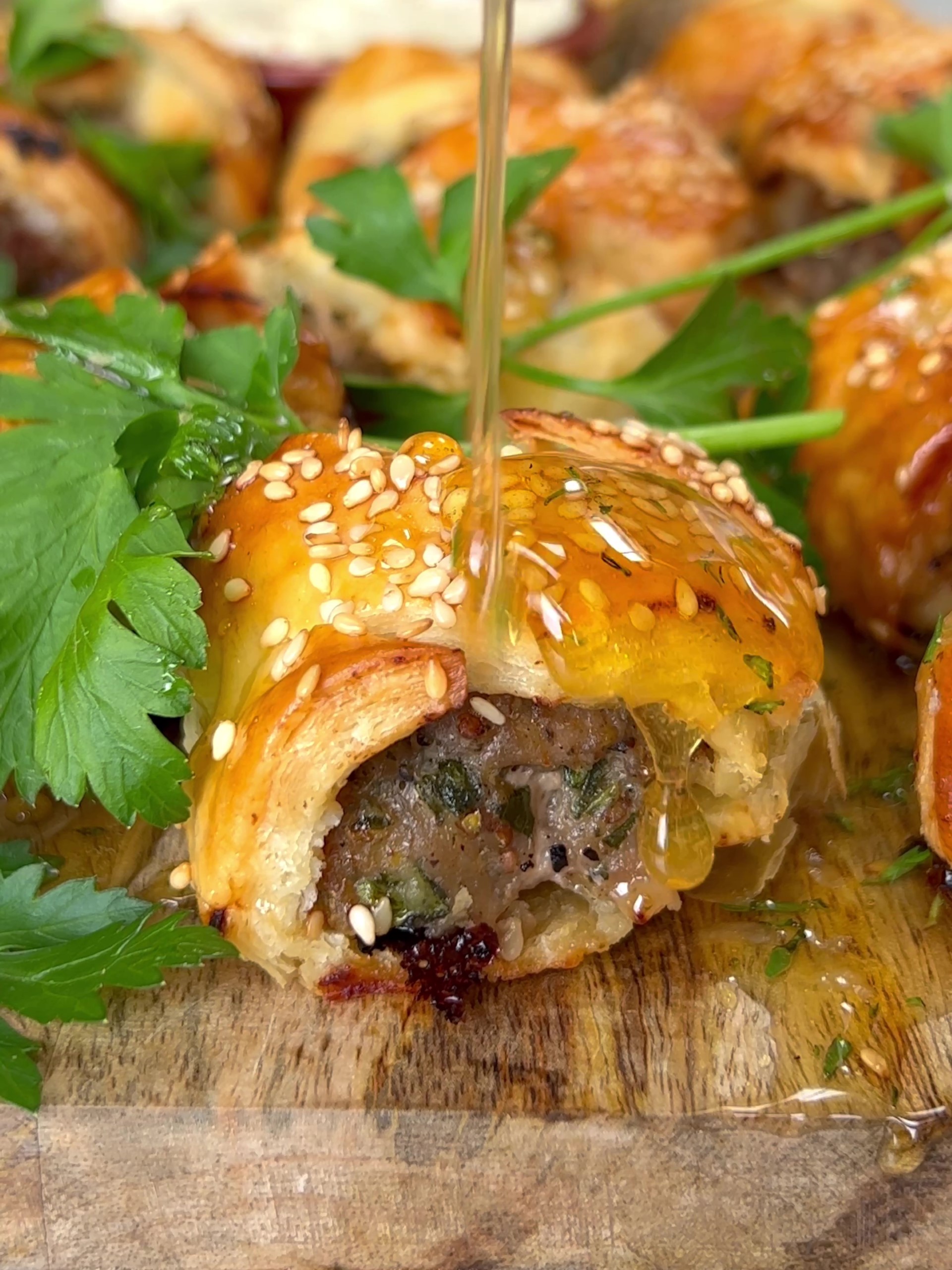 Drizzling sausage rolls with honey dressing.