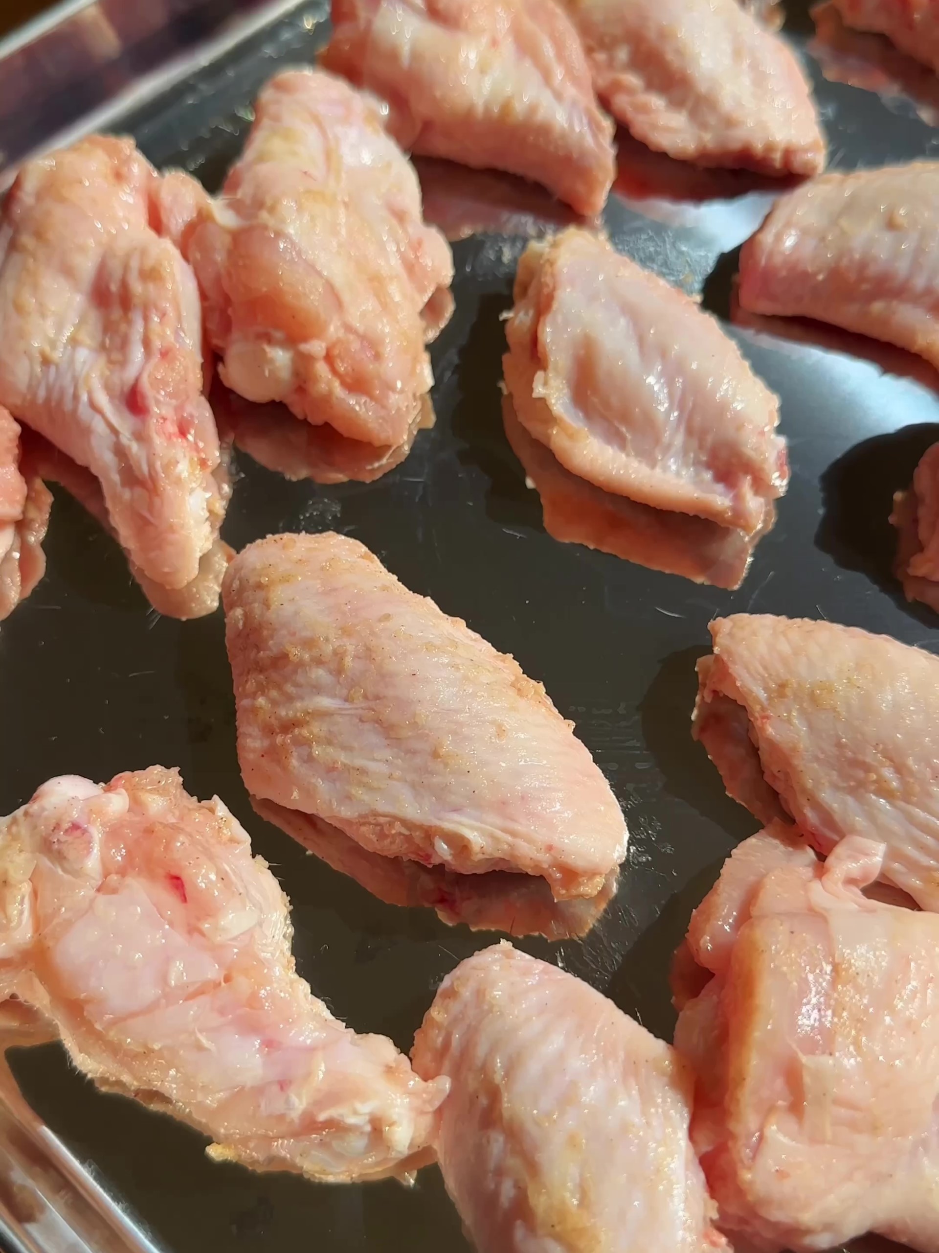  Placing the chicken wings well-spaced apart onto the prepared baking tray.