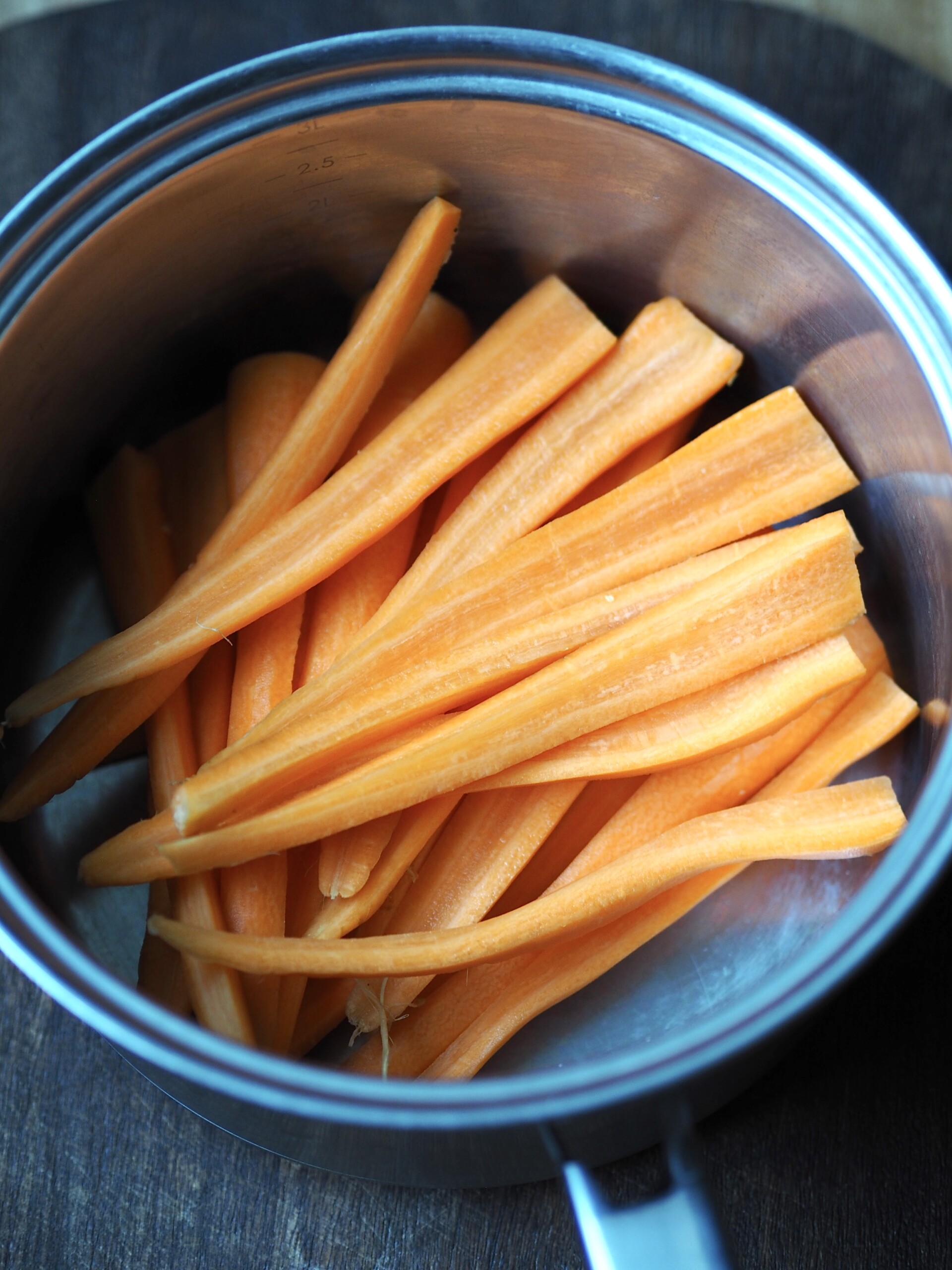 Cut carrot batons in a saucepan.