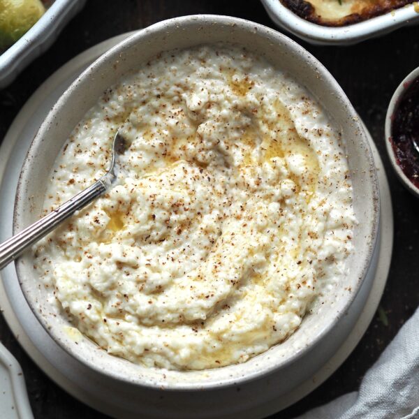 Close up of a bowl of bread sauce topped with melted butter and grated nutmeg.