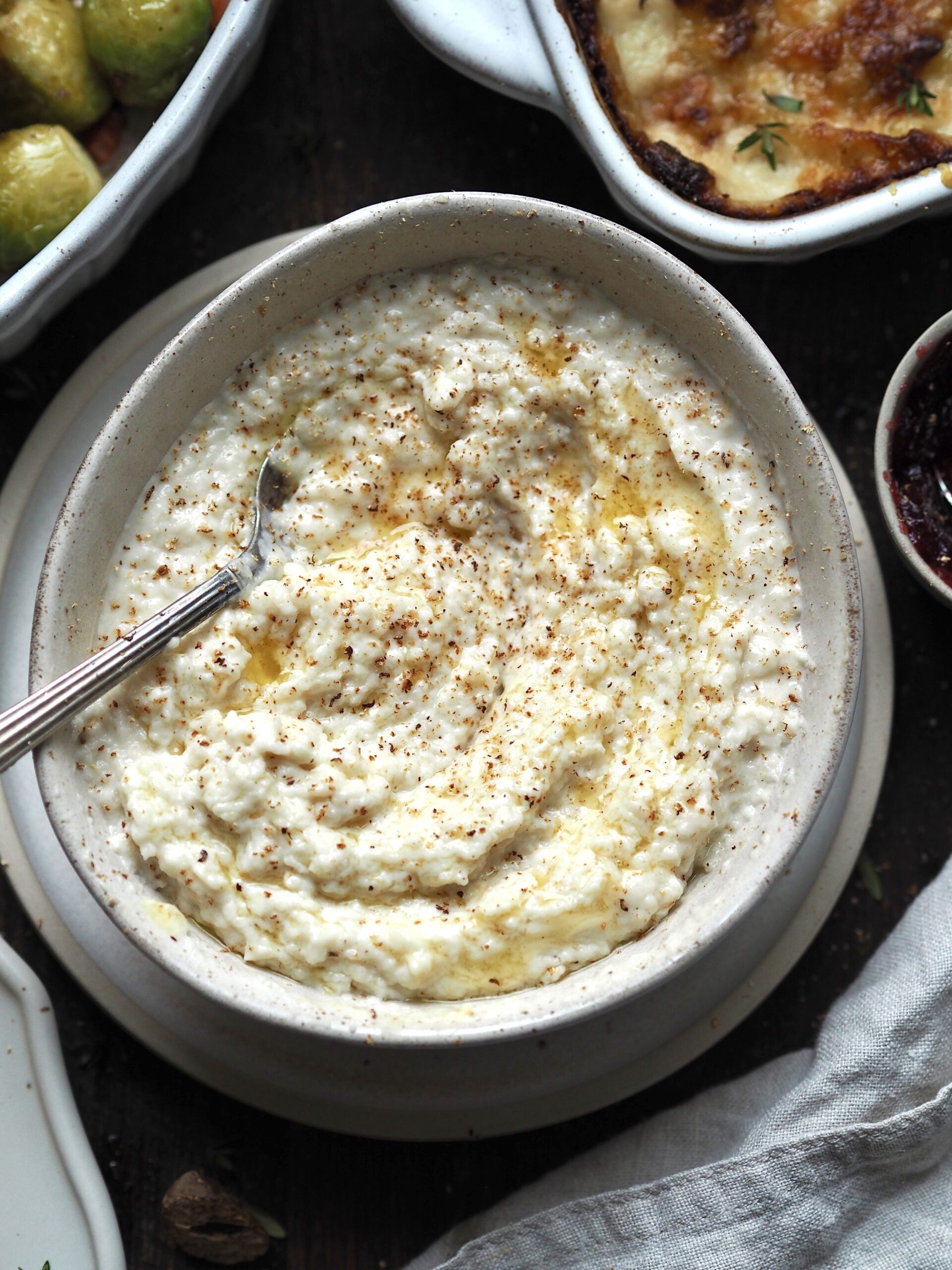 Close up of a bowl of bread sauce topped with melted butter and grated nutmeg. 