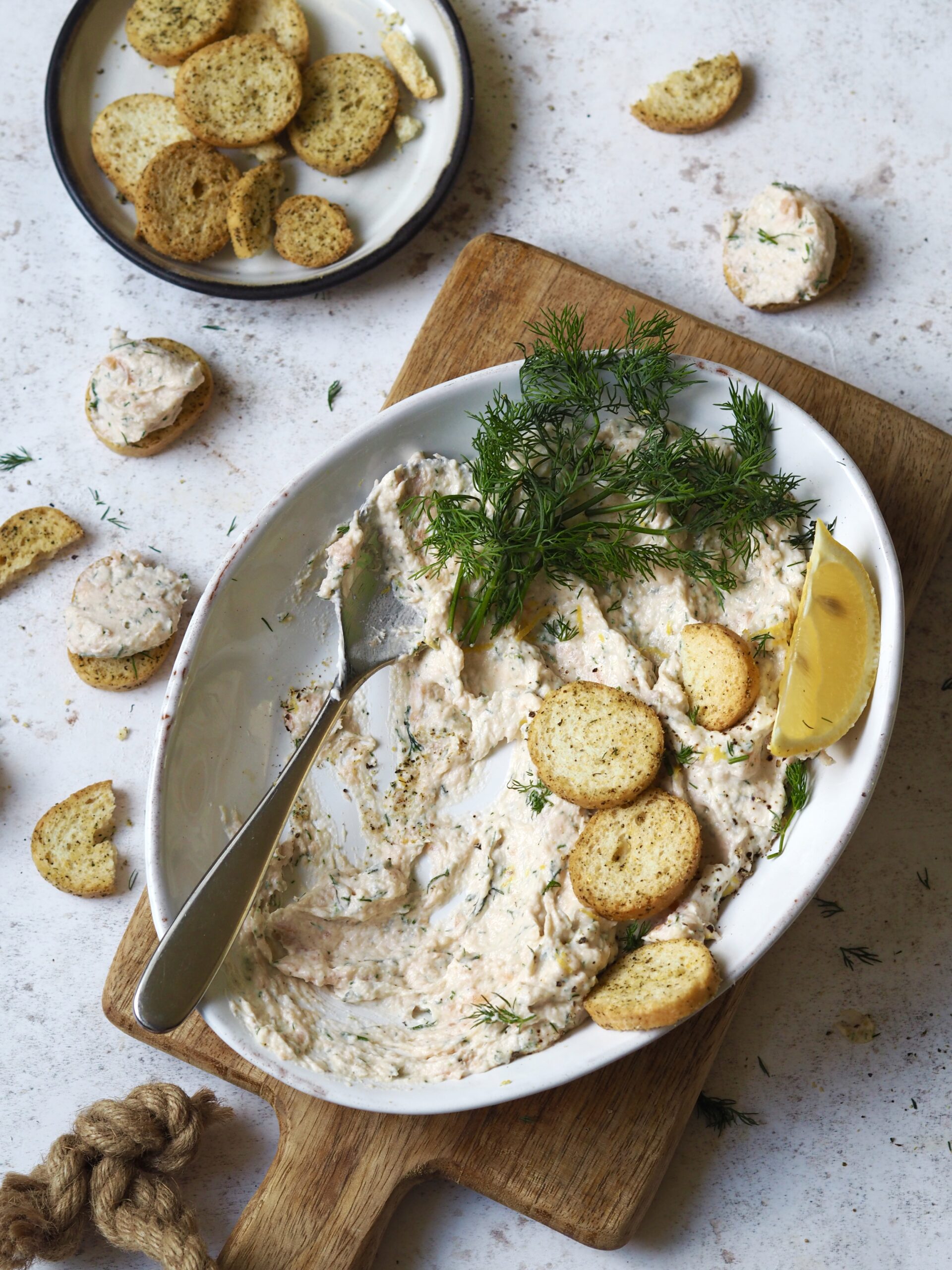 Smoked salmon pate being spooned onto crostini.