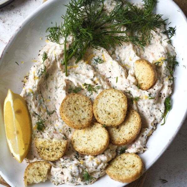 Plate of smoked salmon pate topped with fresh dill and mini crostini.