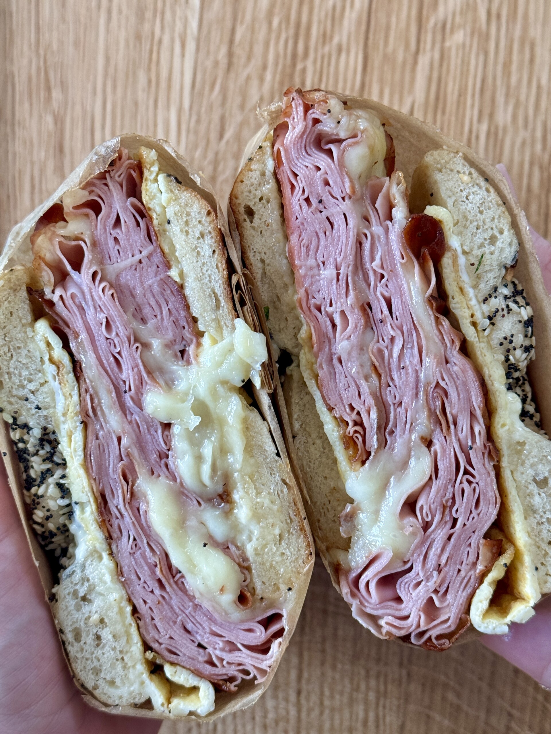 woman holding breakfast bagels sandwiches cut in half.