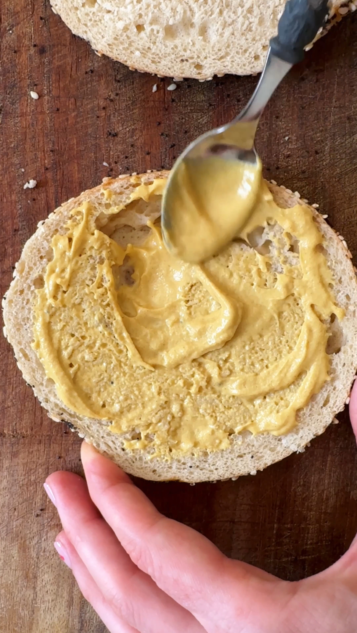 spreading mustard on bagel.