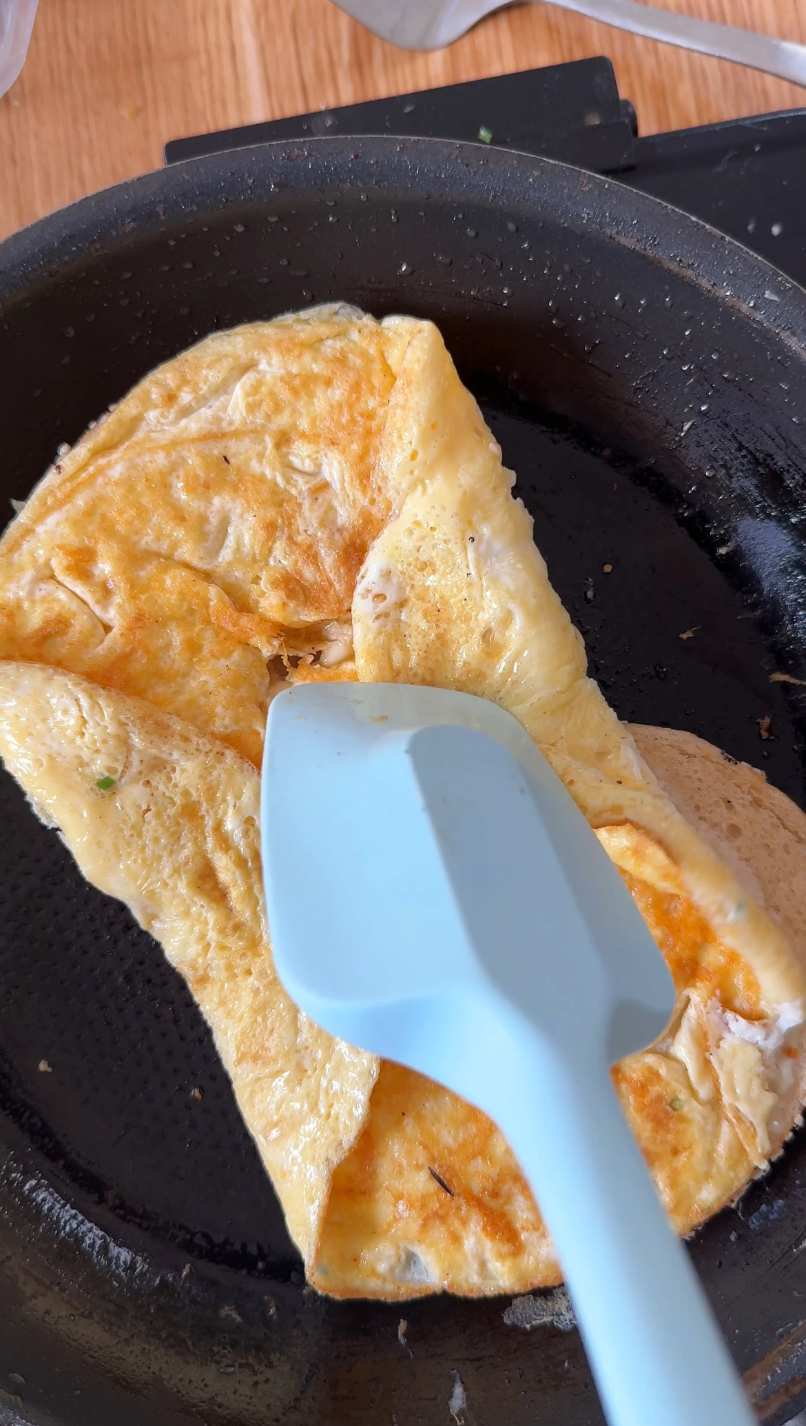 folding egg into a breakfast bagel sandwich.