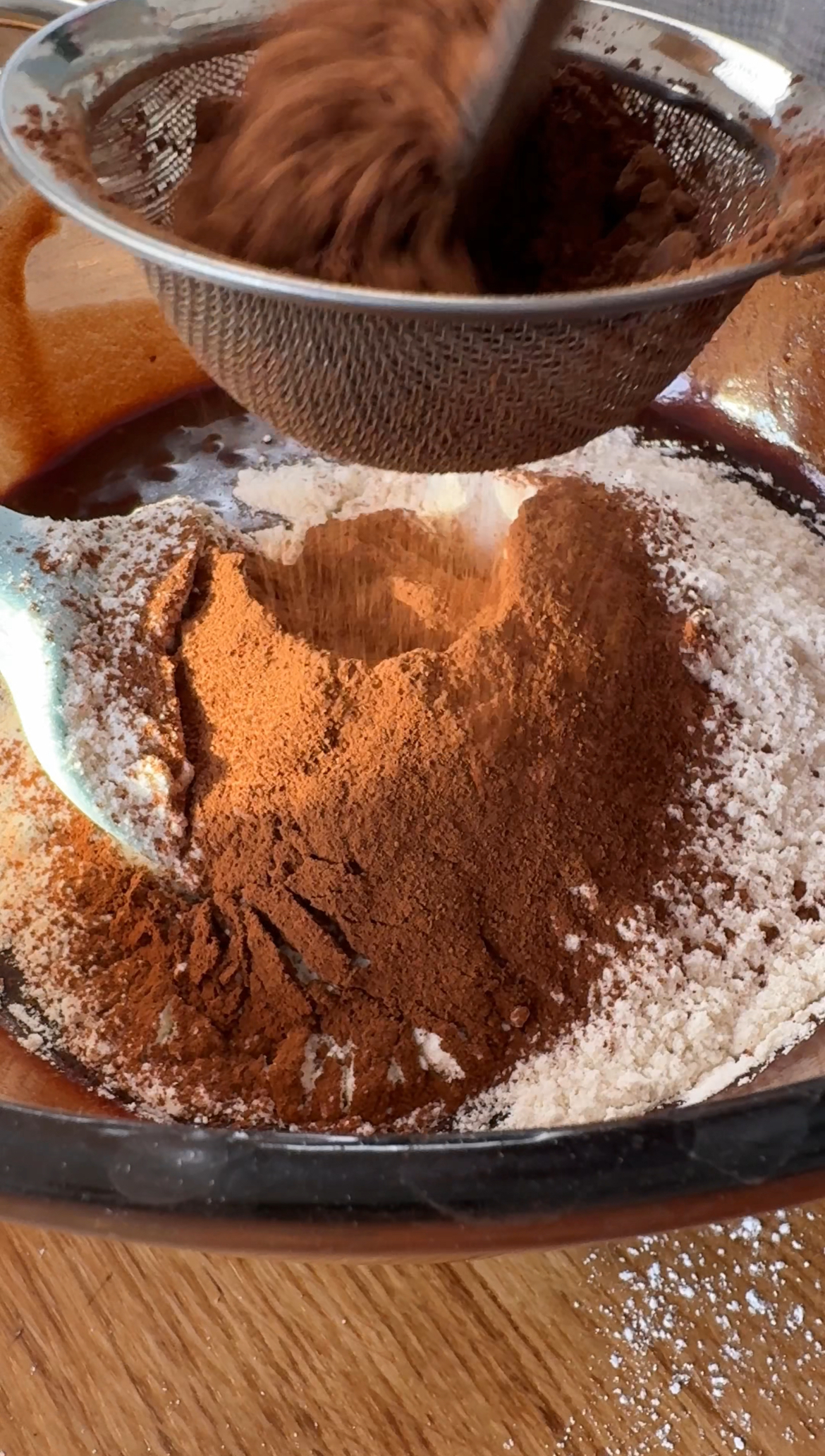 sifting flour and cocoa powder into the brownie batter.