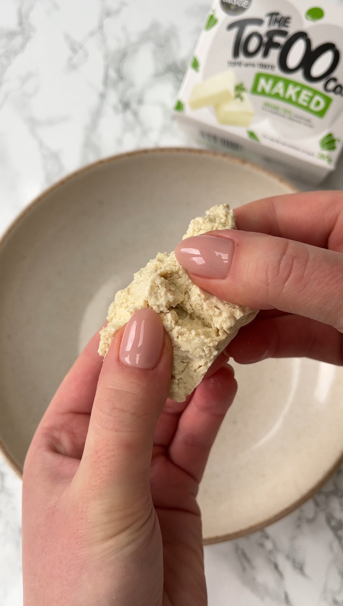 tearing tofu into a bowl by hand