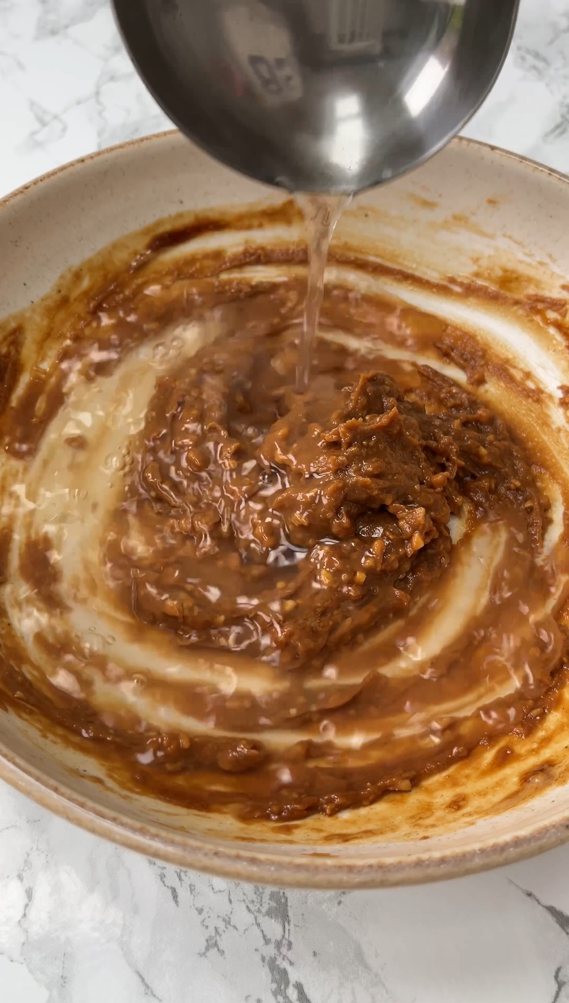 adding a ladle of dashi stock to the soup base