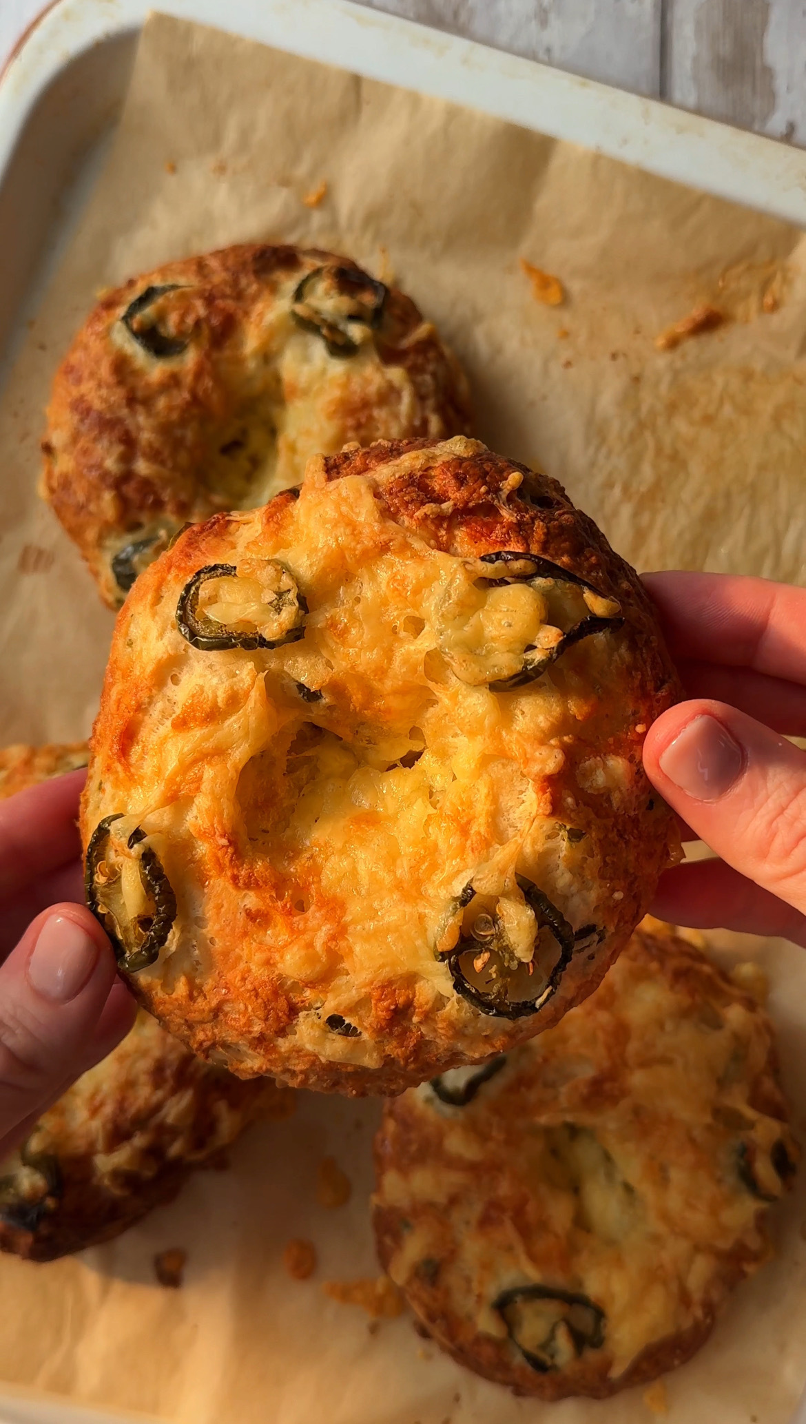 woman holding bagel with cheese and jalapeno.