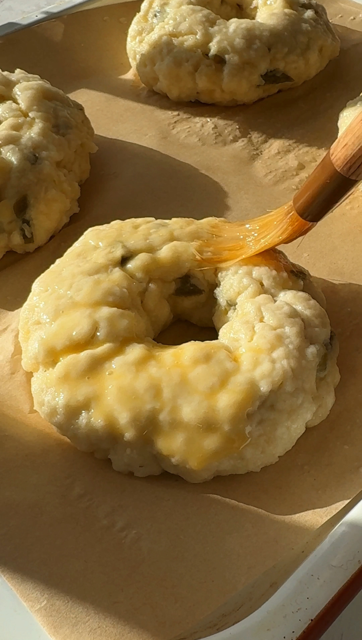 brushing egg wash on to bagel.