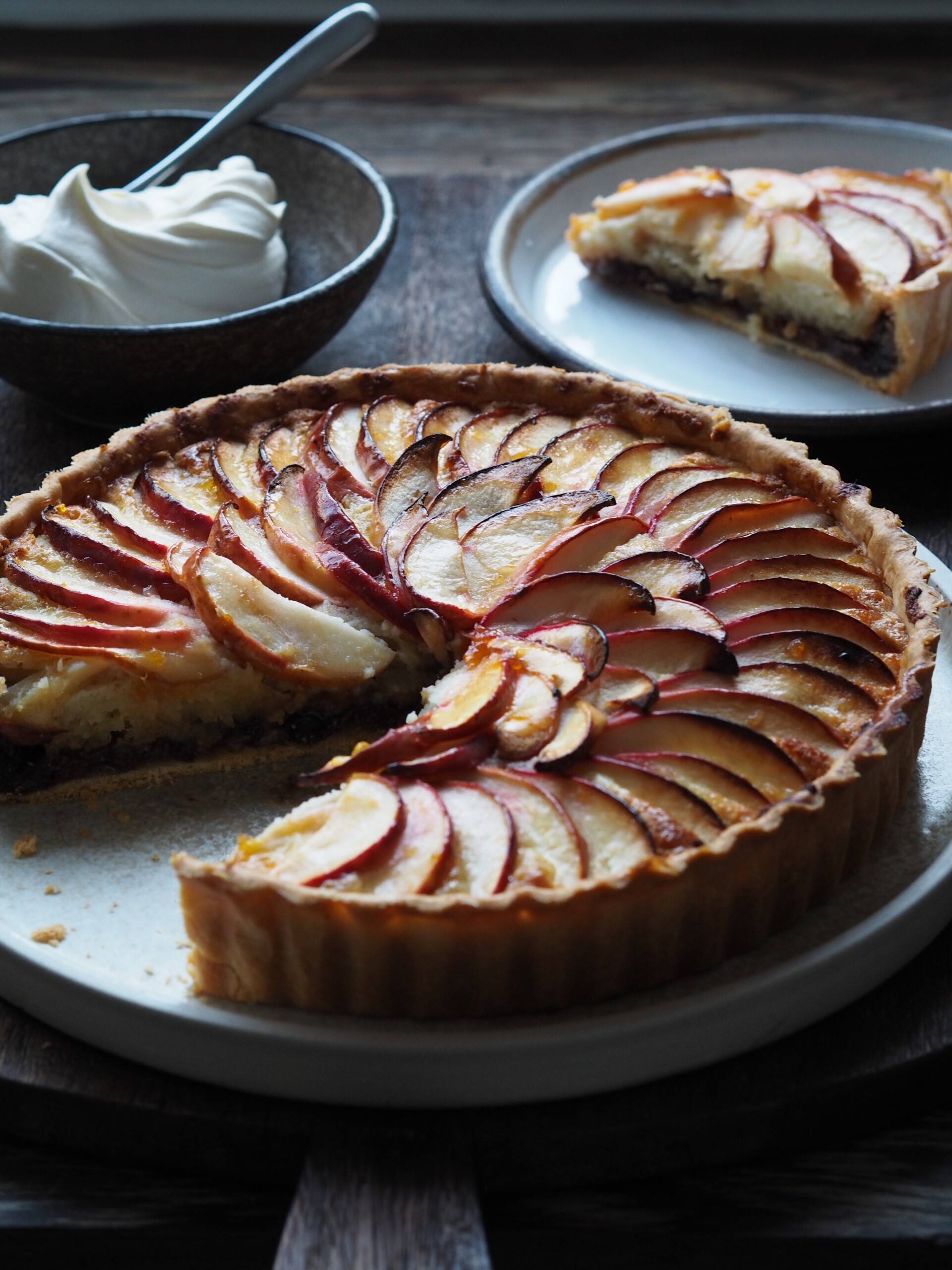 Mincemeat and Frangipane Tart in a baking dish with a slice of tart in a plate.