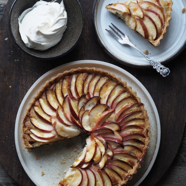 Dish with Mincemeat and Frangipane Tart with a slice in a plate and a bowl of cream