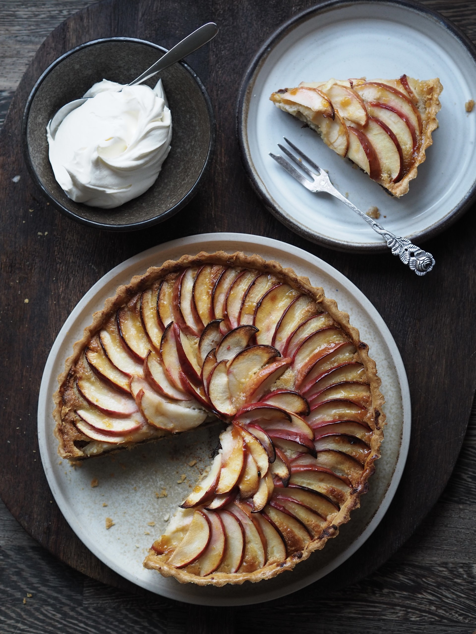 Dish with Mincemeat and Frangipane Tart with a slice in a plate and a bowl of cream