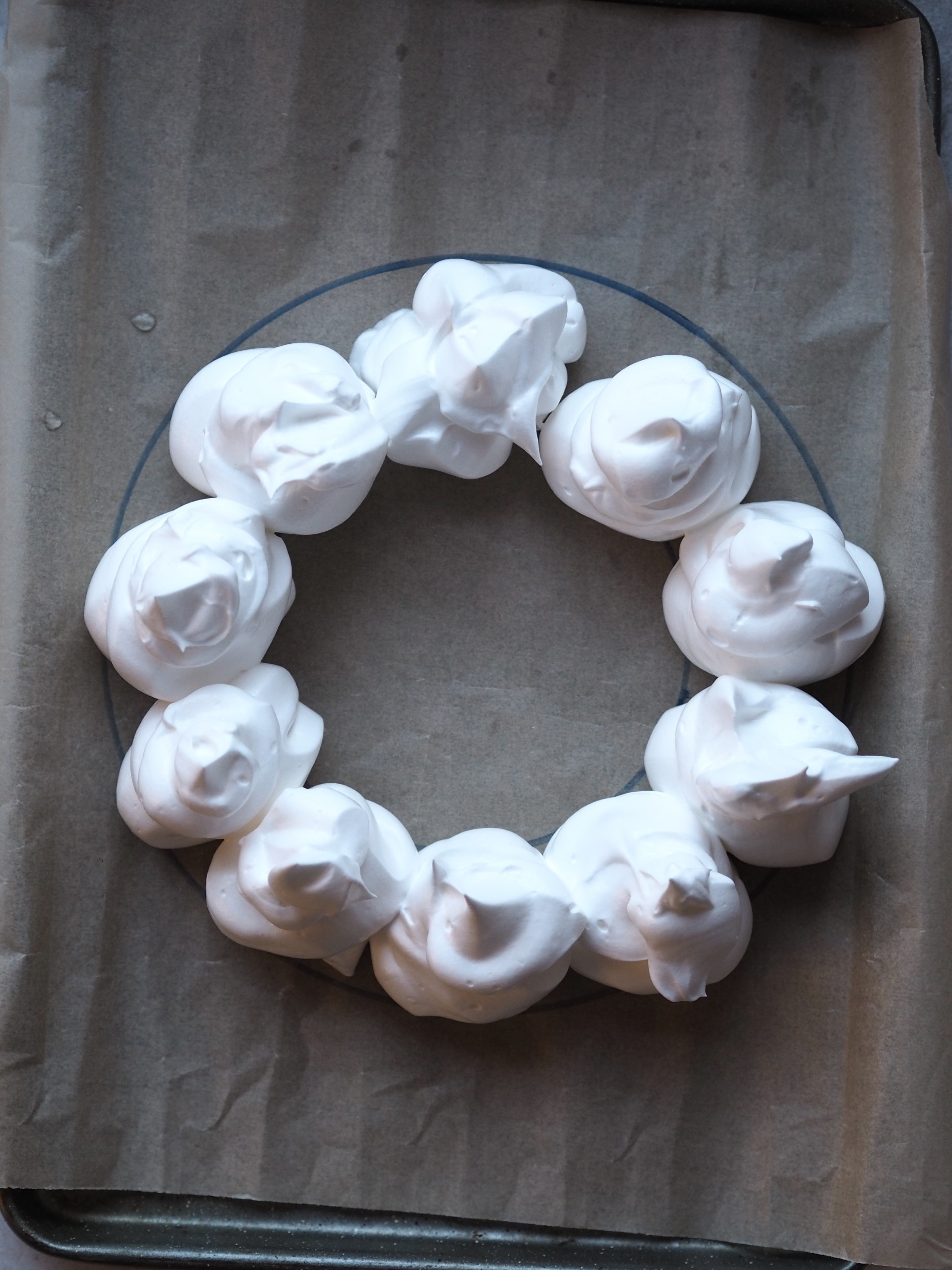 Piping the meringue into circles inside the circle to make a wreath shape. 