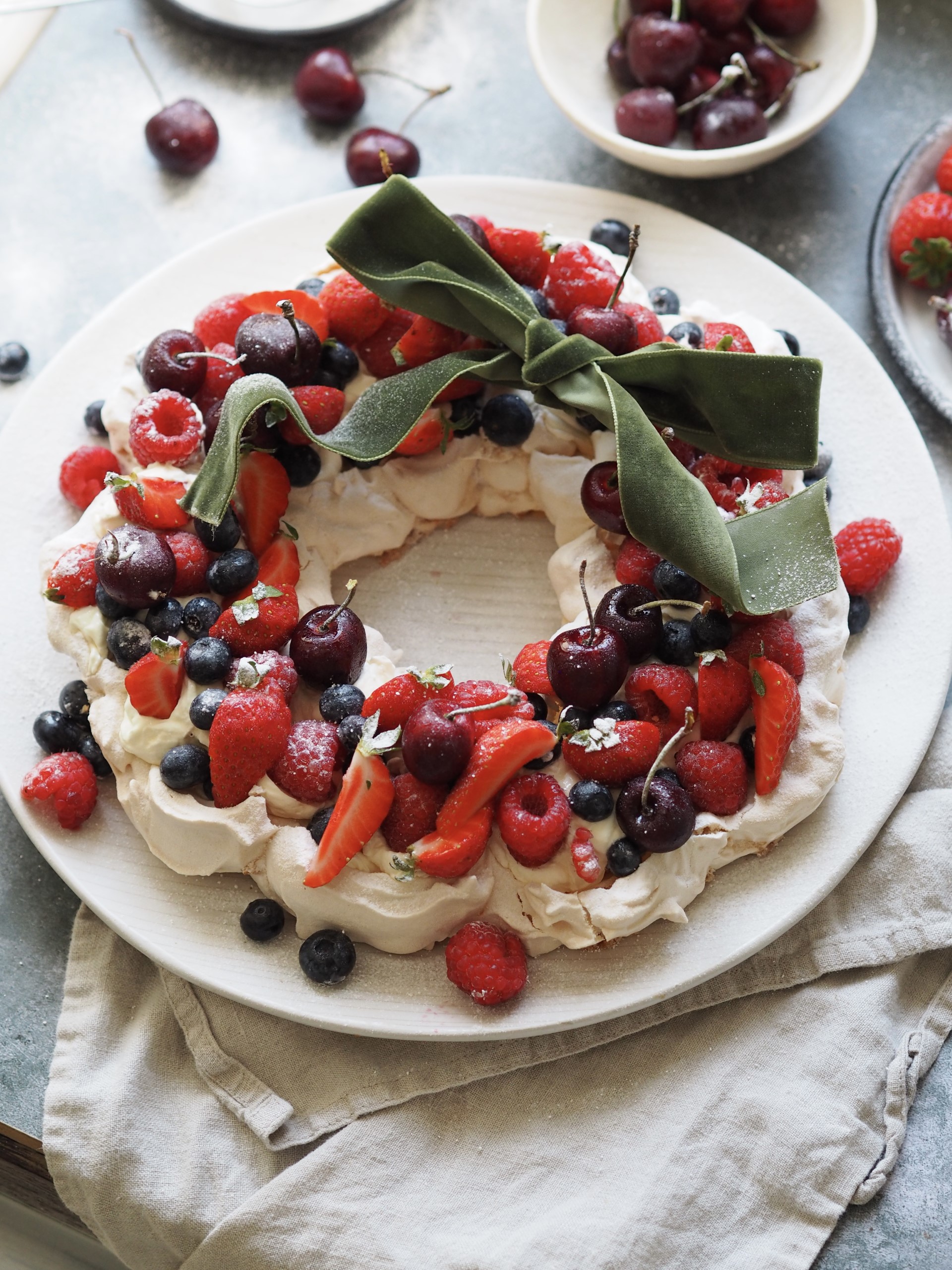 Topping the pavlova with berries and a ribbon