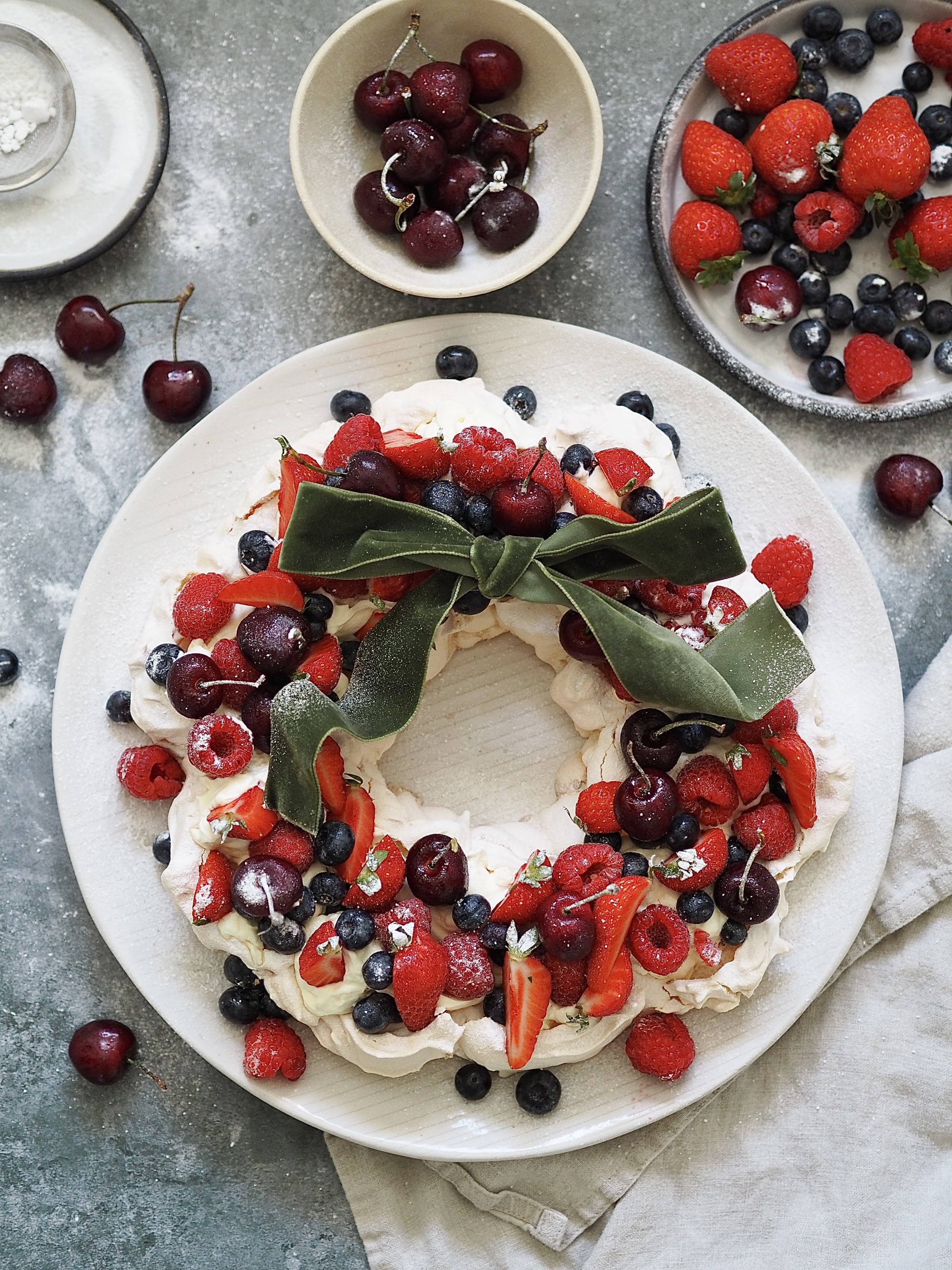 Christmas Pavlova on a plate with bowls of berries