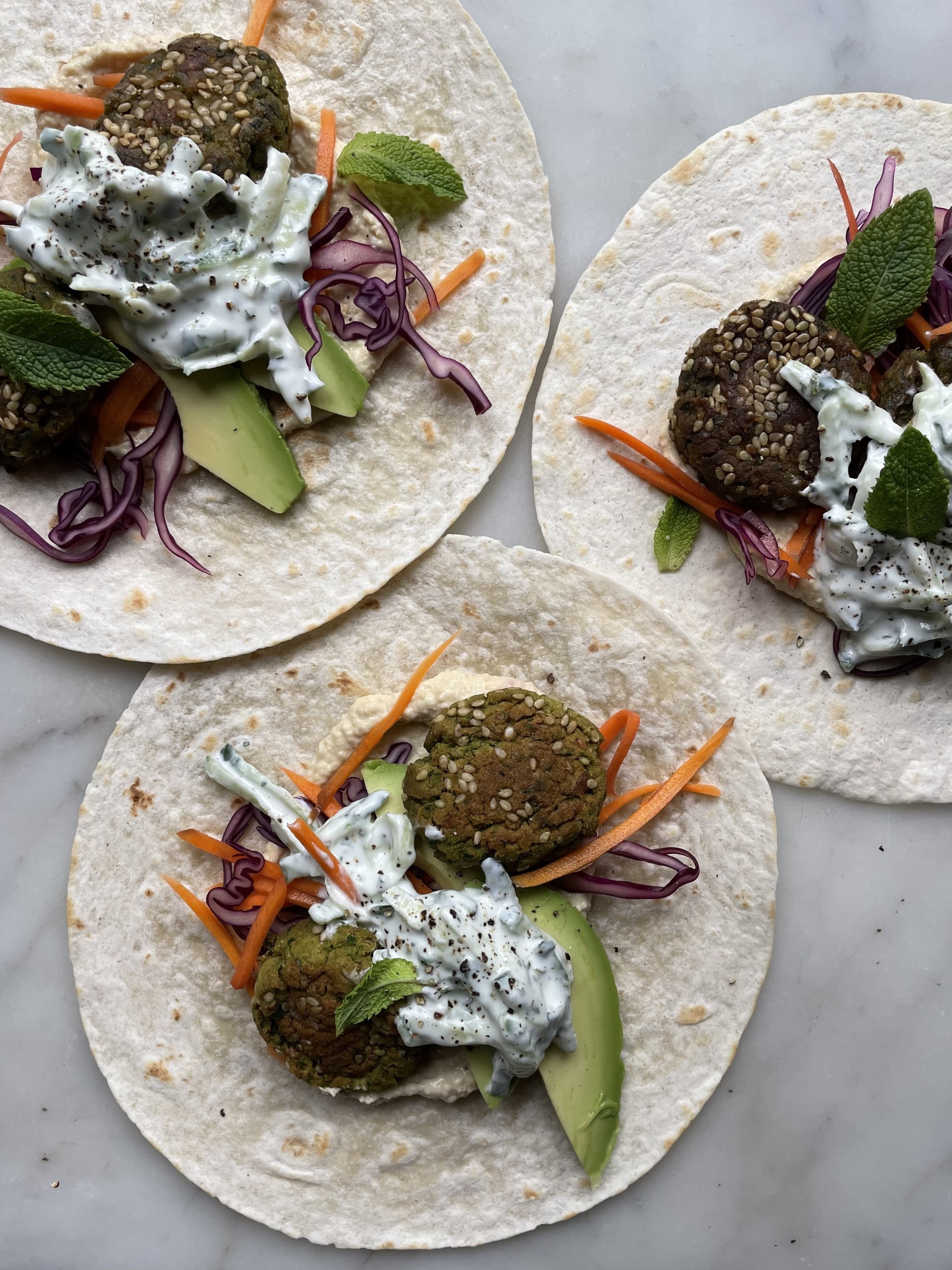 Three filled Baked Herby Falafel with Tzatziki on a tortilla