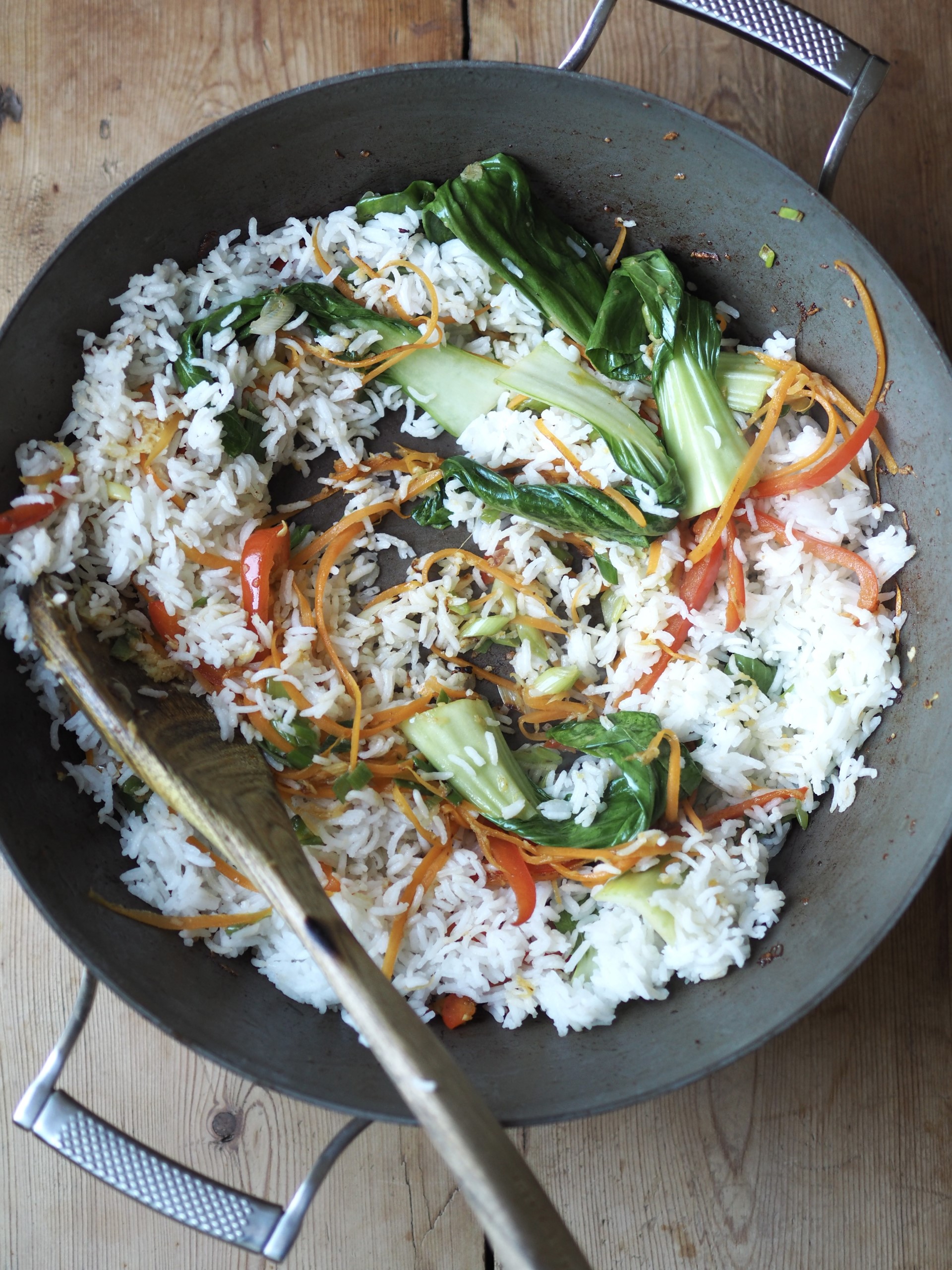 Adding the rice in a pan with vegetables, shrimp and chicken