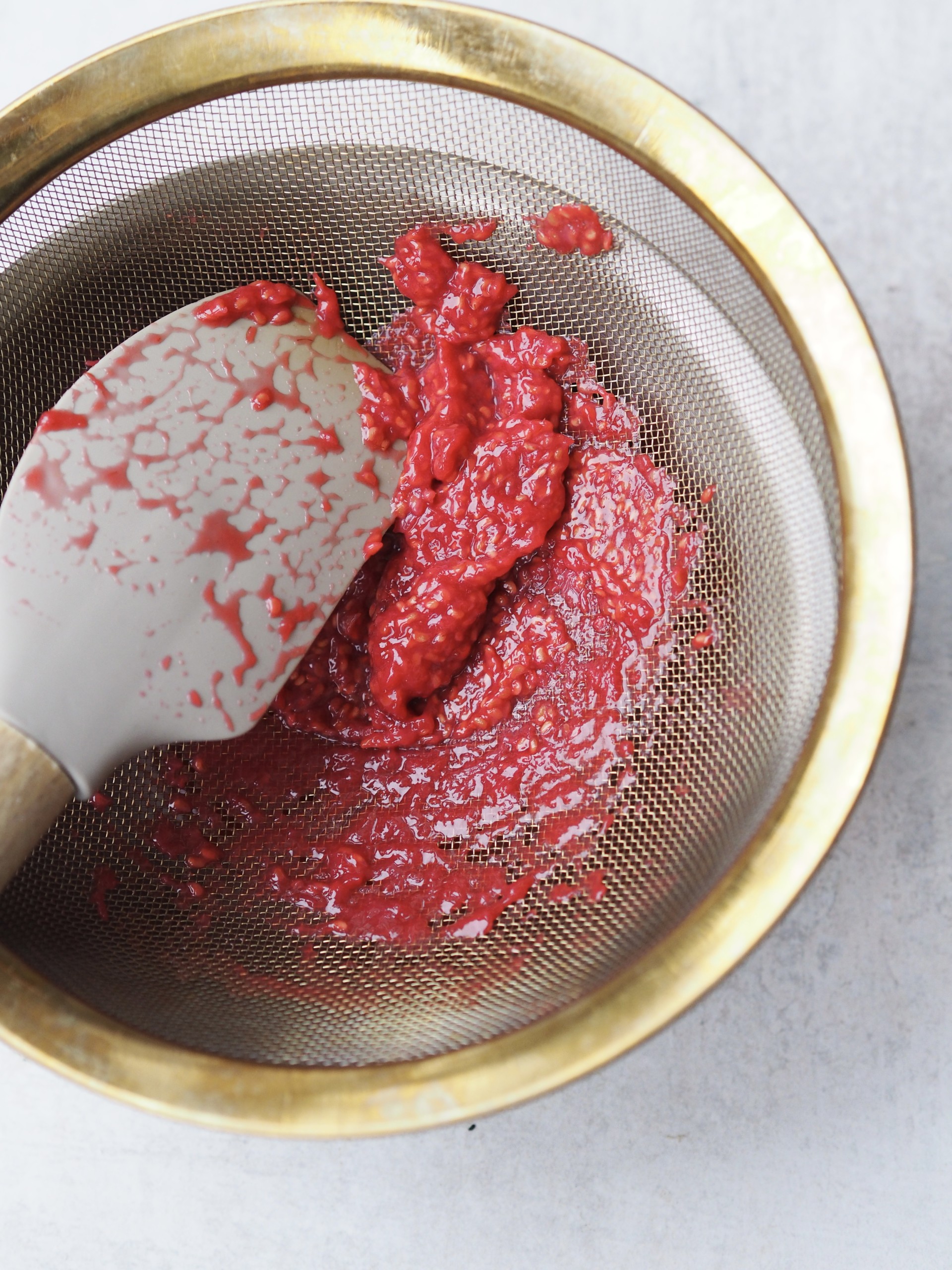 Straining raspberries through a sieve