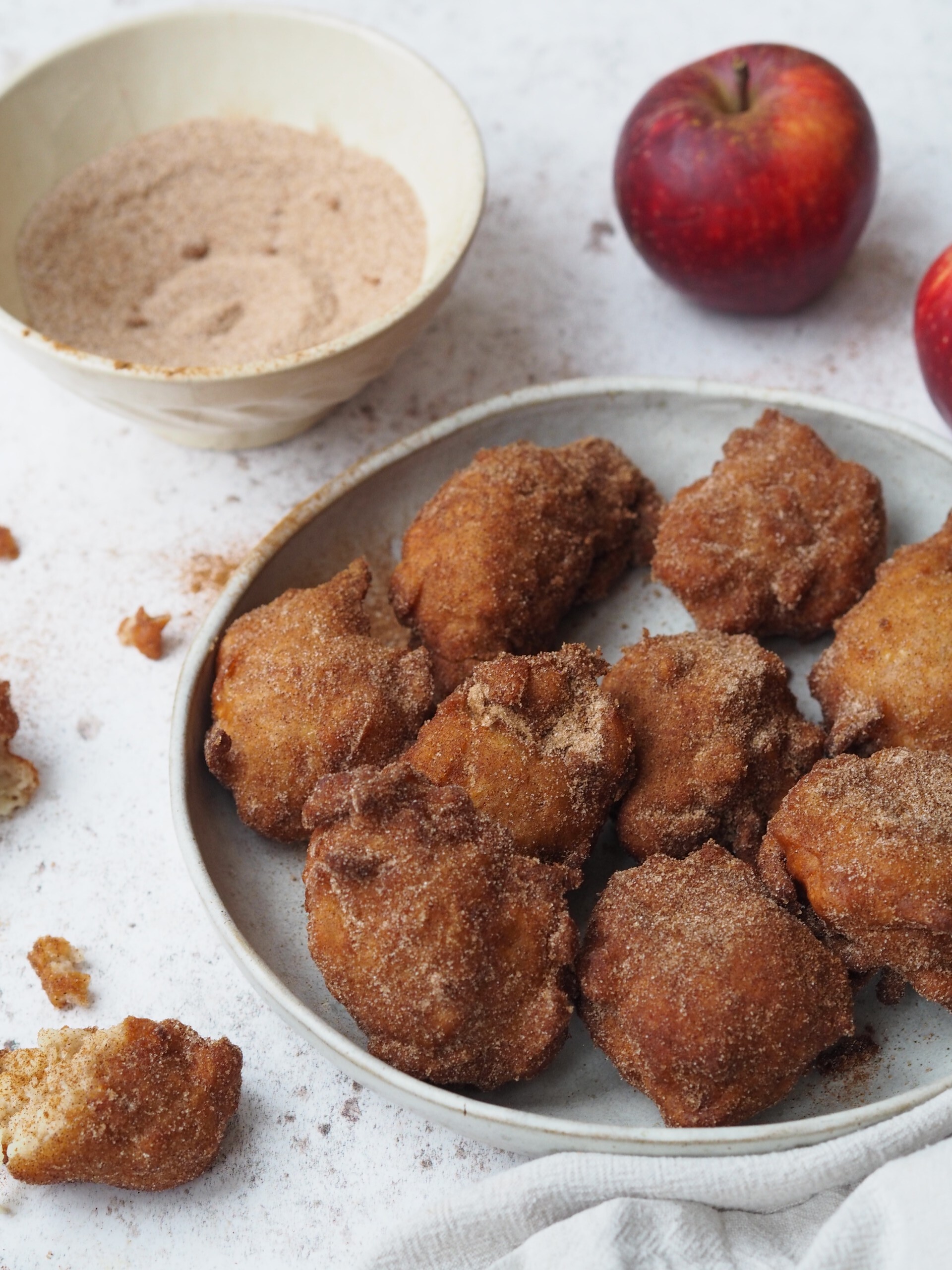 Apple Sauce Fritters in a plate with a bowl of cinnamon sugar