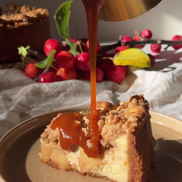 Drizzling caramel sauce over a slice of Apple Crumble Cheesecake.