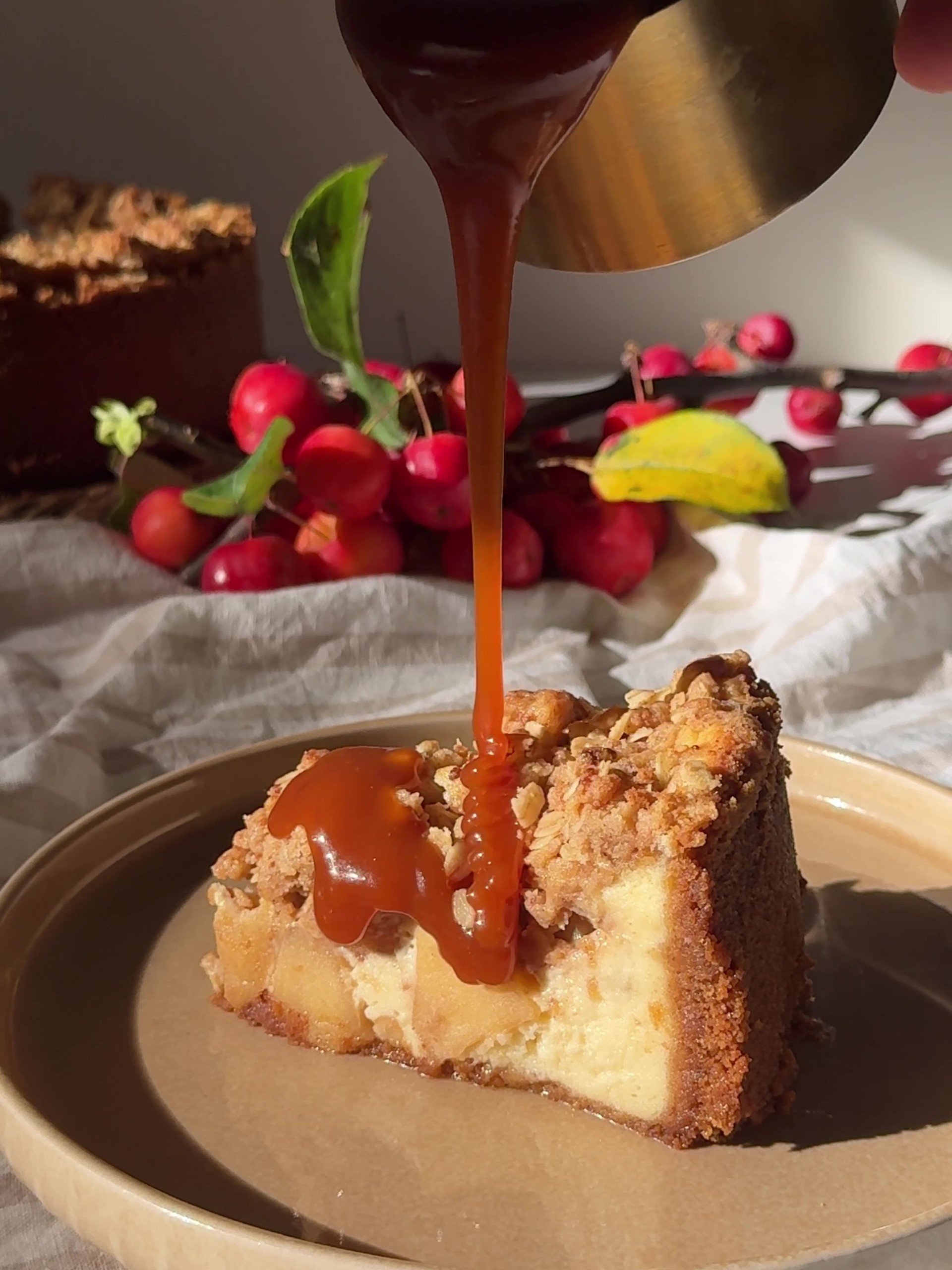 Drizzling caramel sauce over a slice of Apple Crumble Cheesecake