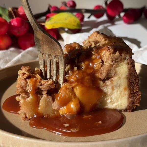 A clice of Apple Crumble Cheesecake with caramel sauce