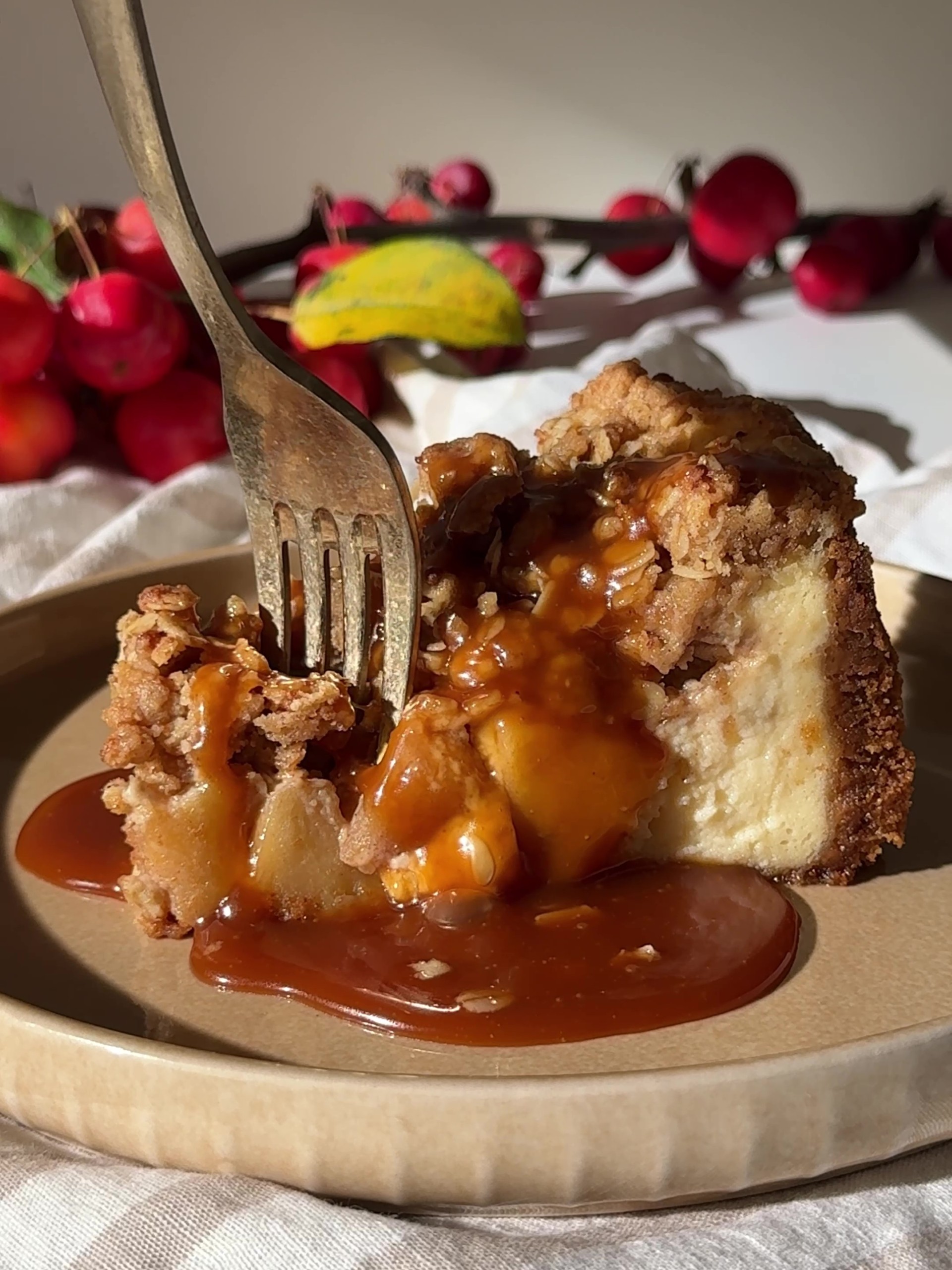 A slice of Apple Crumble Cheesecake with caramel sauce.