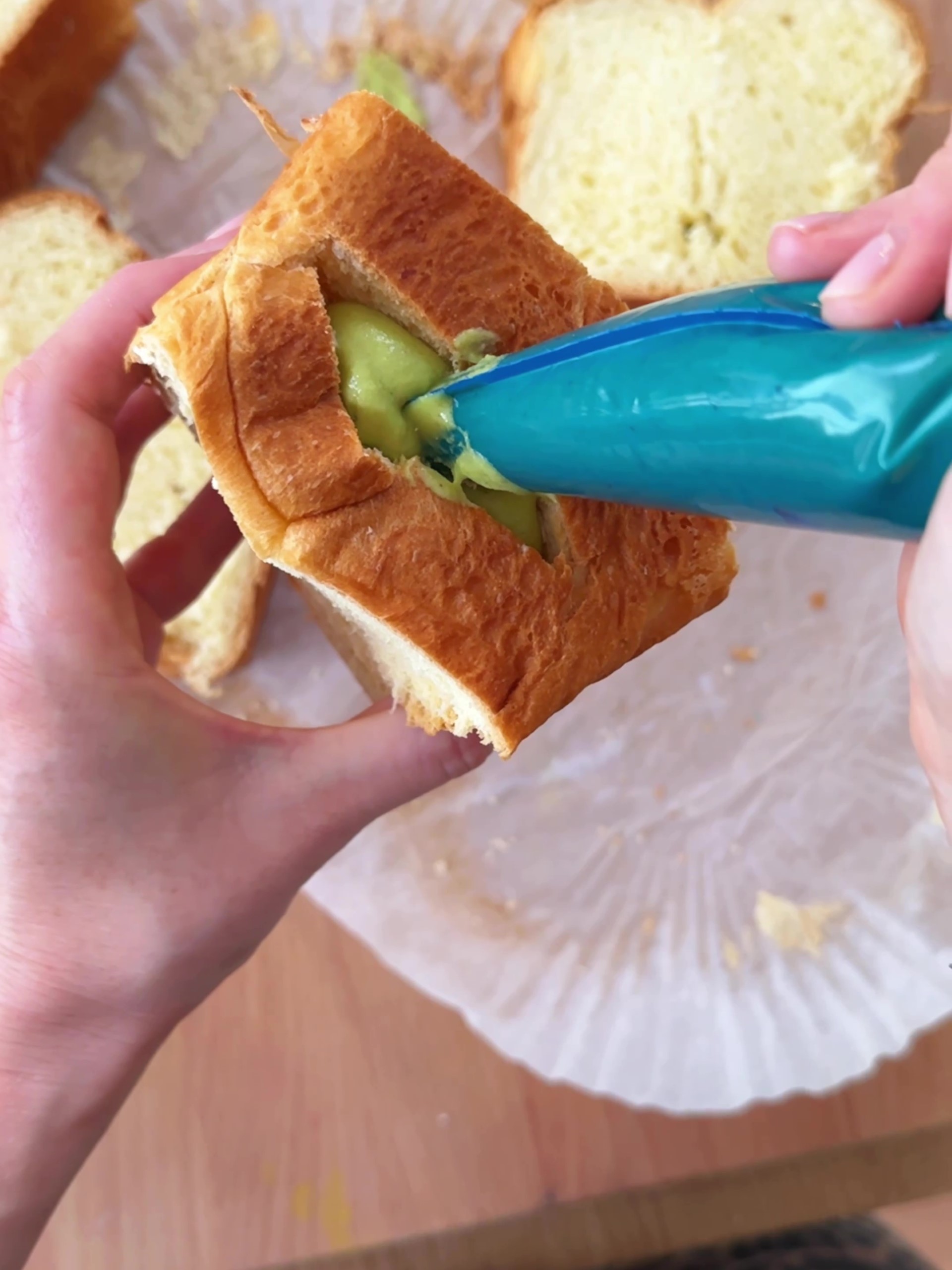 Piping in a generous amount pistachio cream into the Brioche 