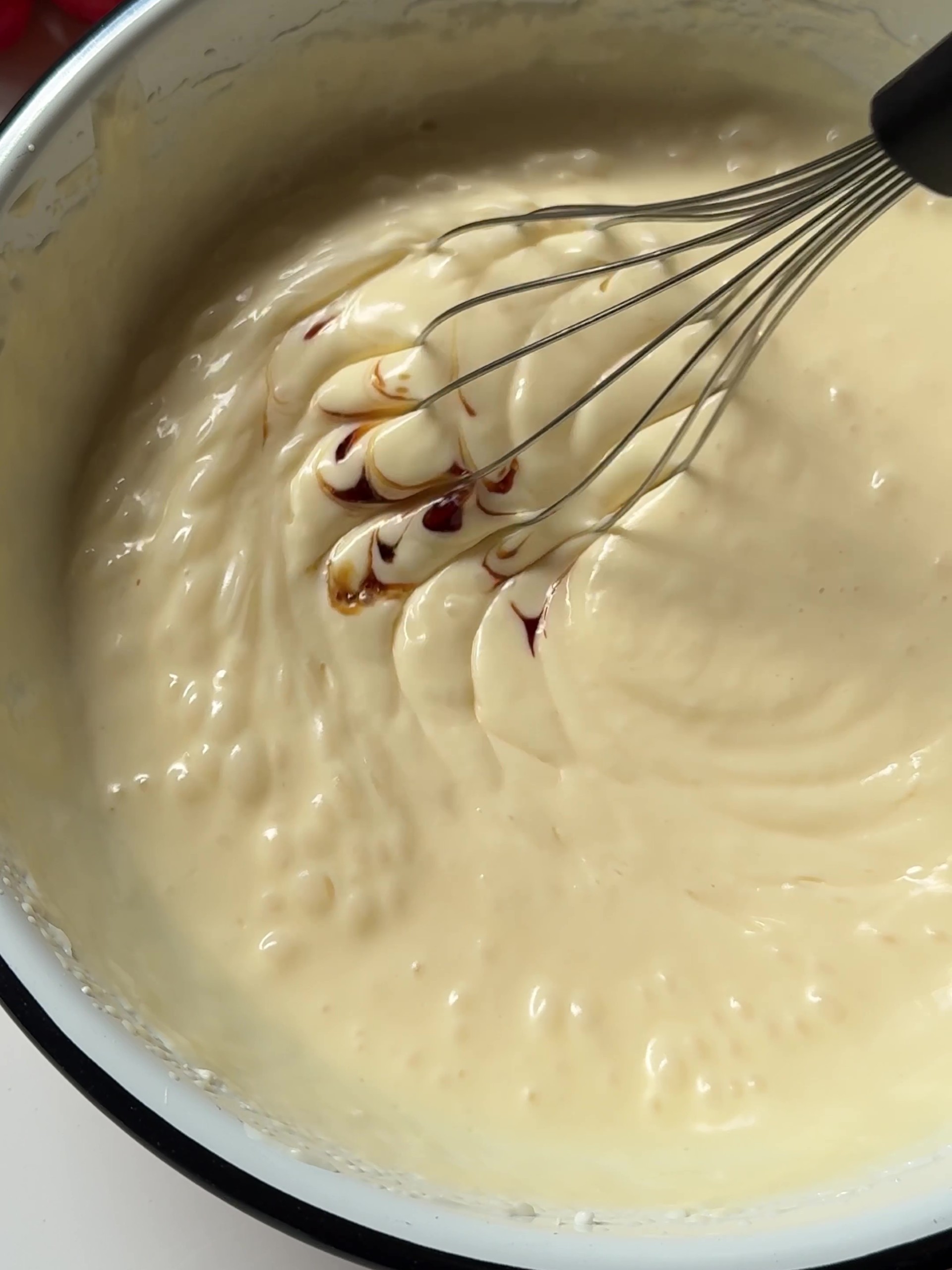 Whisking cheesecake filling and adding vanilla