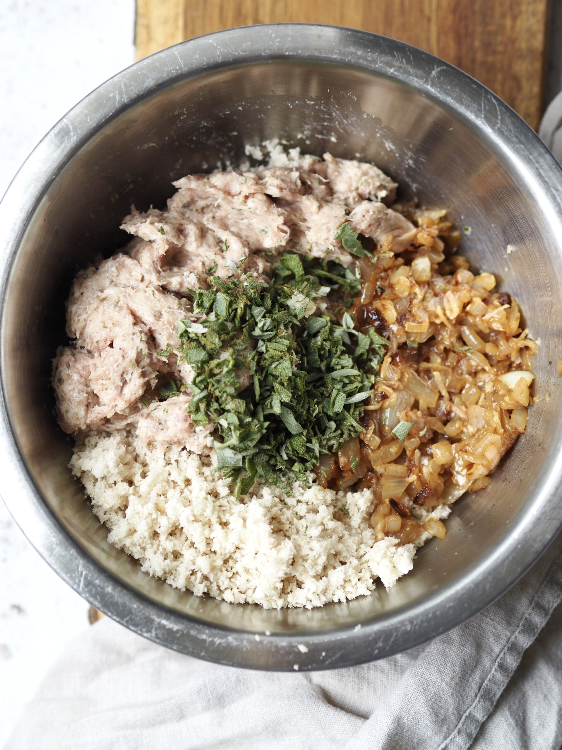 Ingredients for sausage stuffing in a metal mixing bowl.