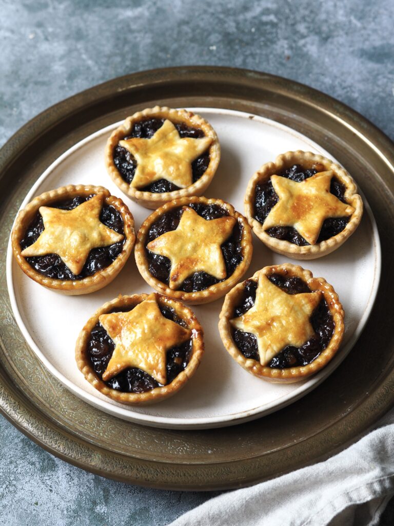 Plate of six mince pies topped with pastry stars.