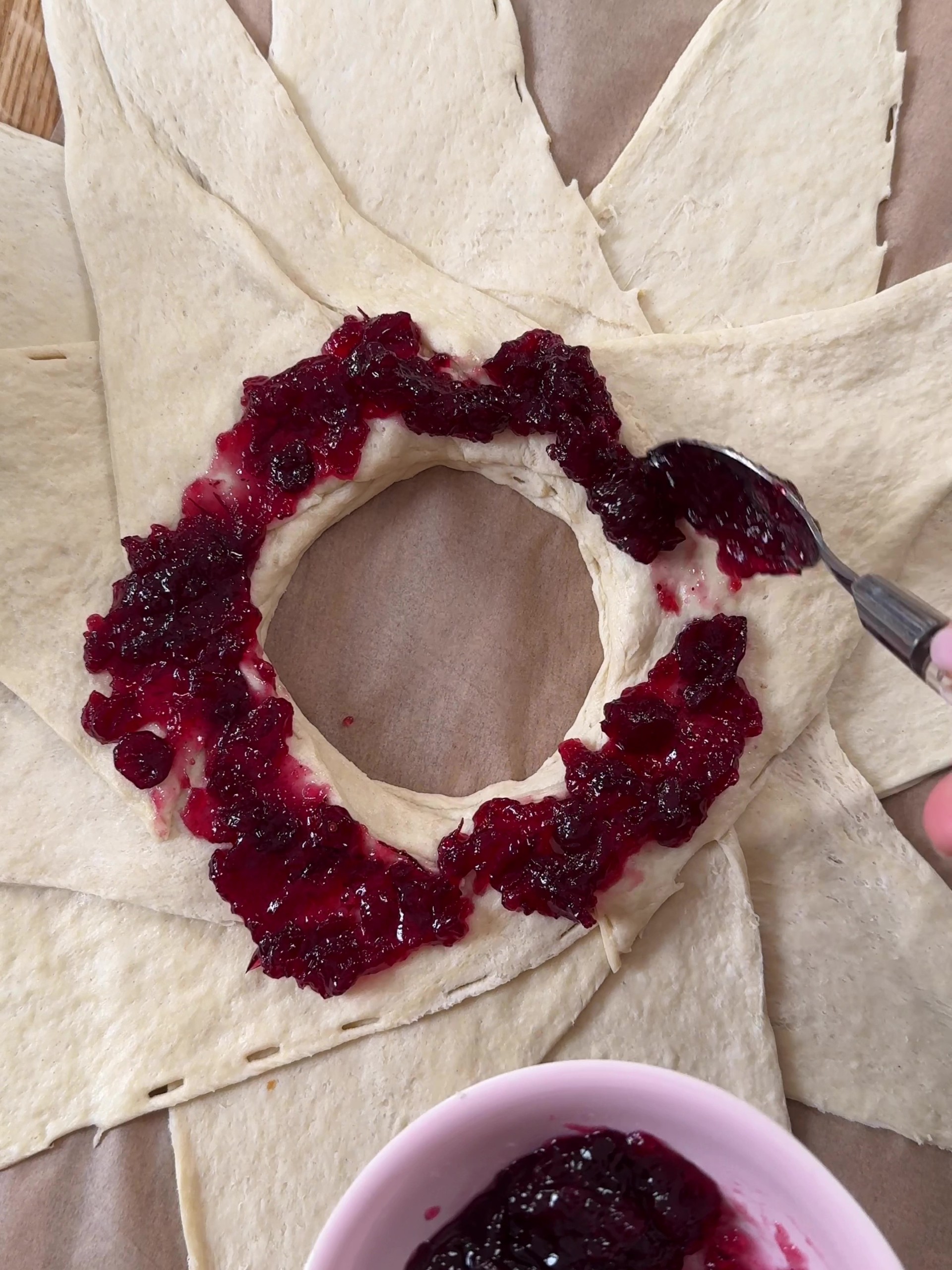 Adding cranberry sauce around the croissant dough