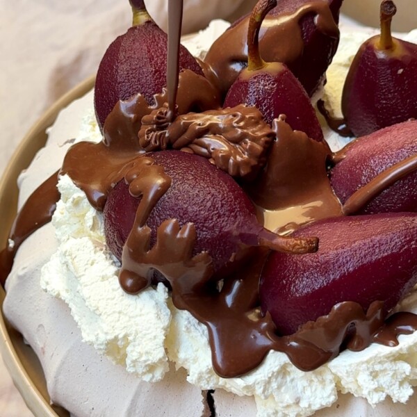 Drizzling chocolate sauce over poached pear Pavlova