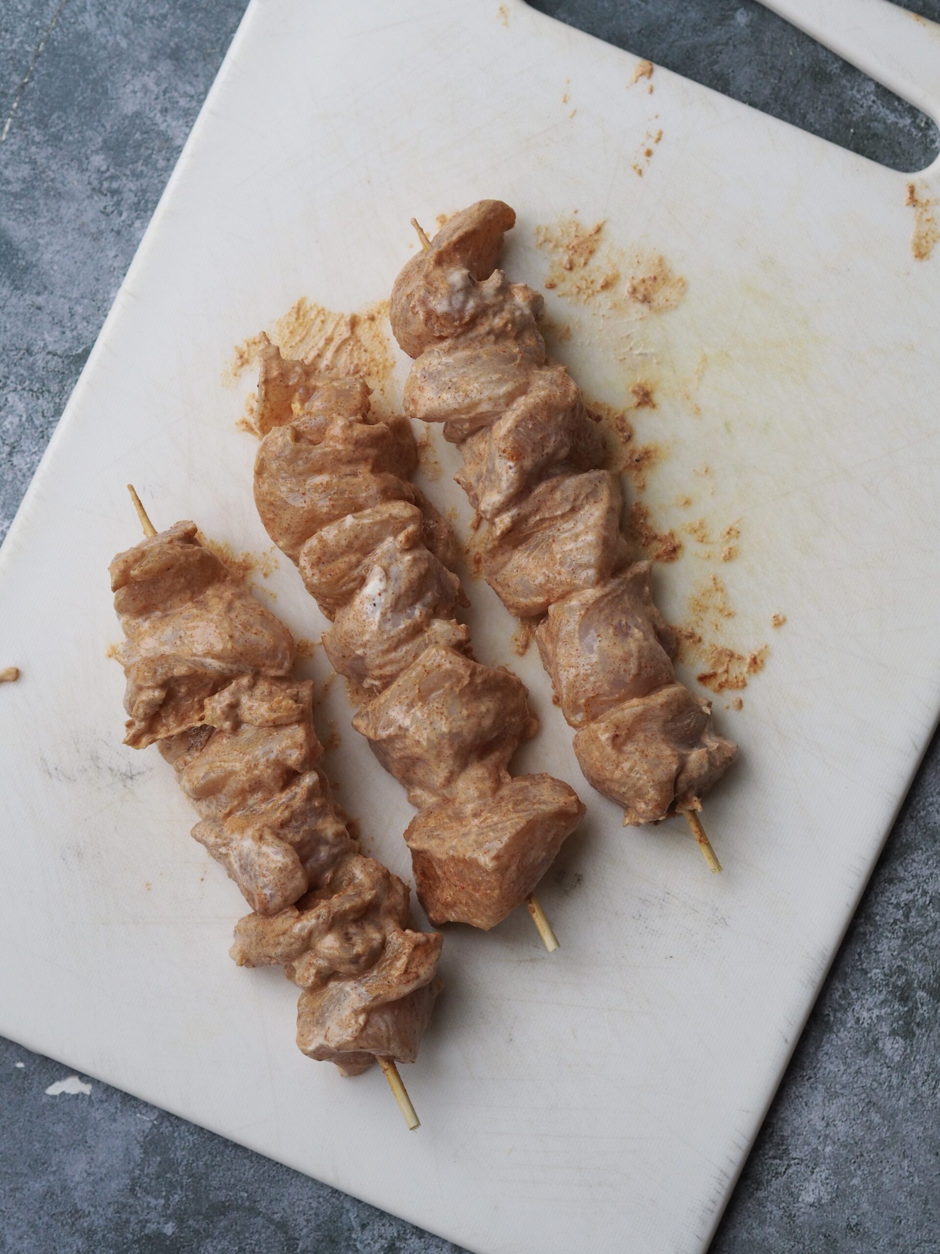 threading chicken onto the skewers.