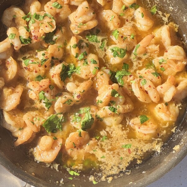 buttered garlic prawns in frying pan with parsley.