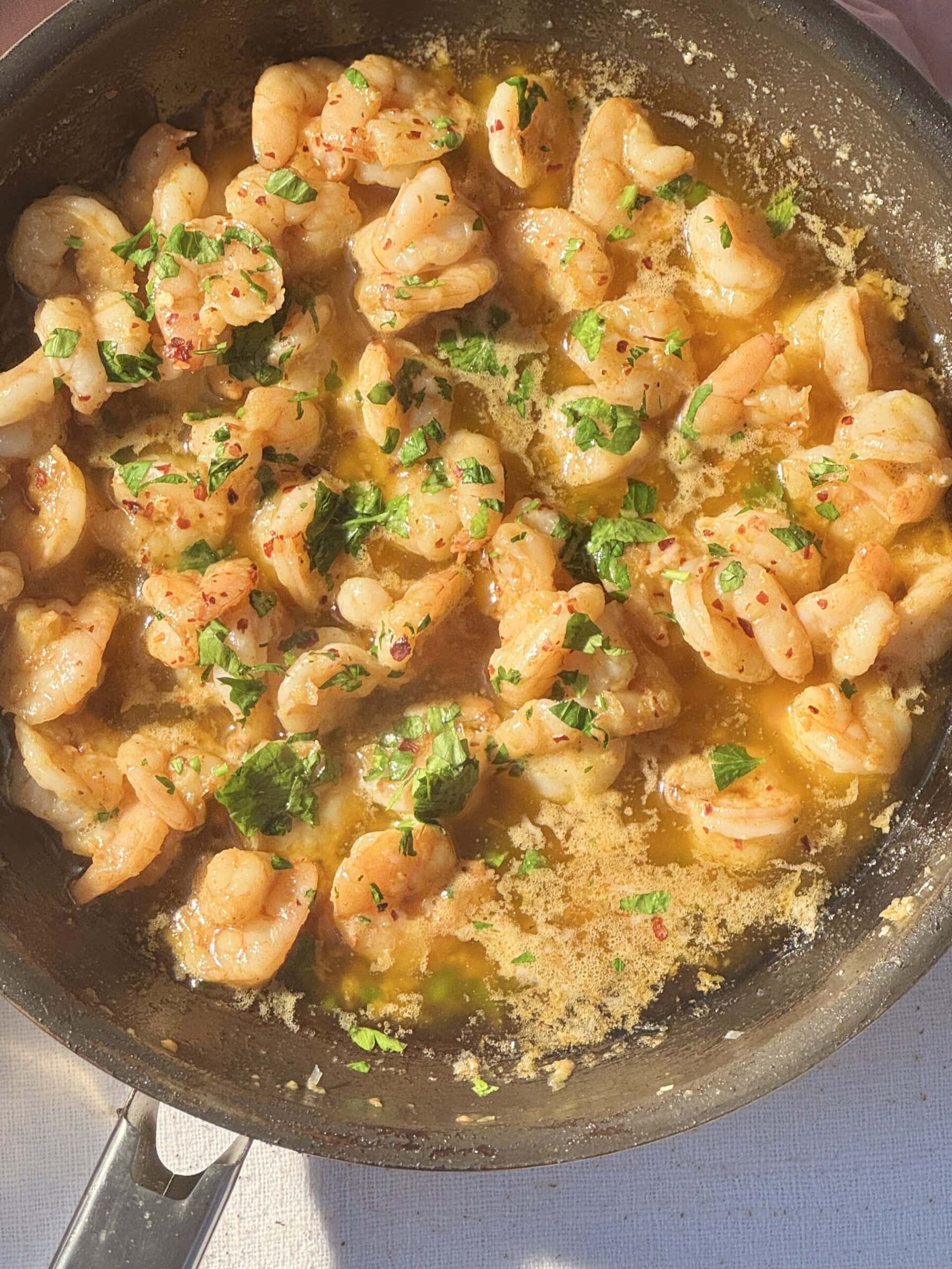 buttered garlic prawns in frying pan with parsley.