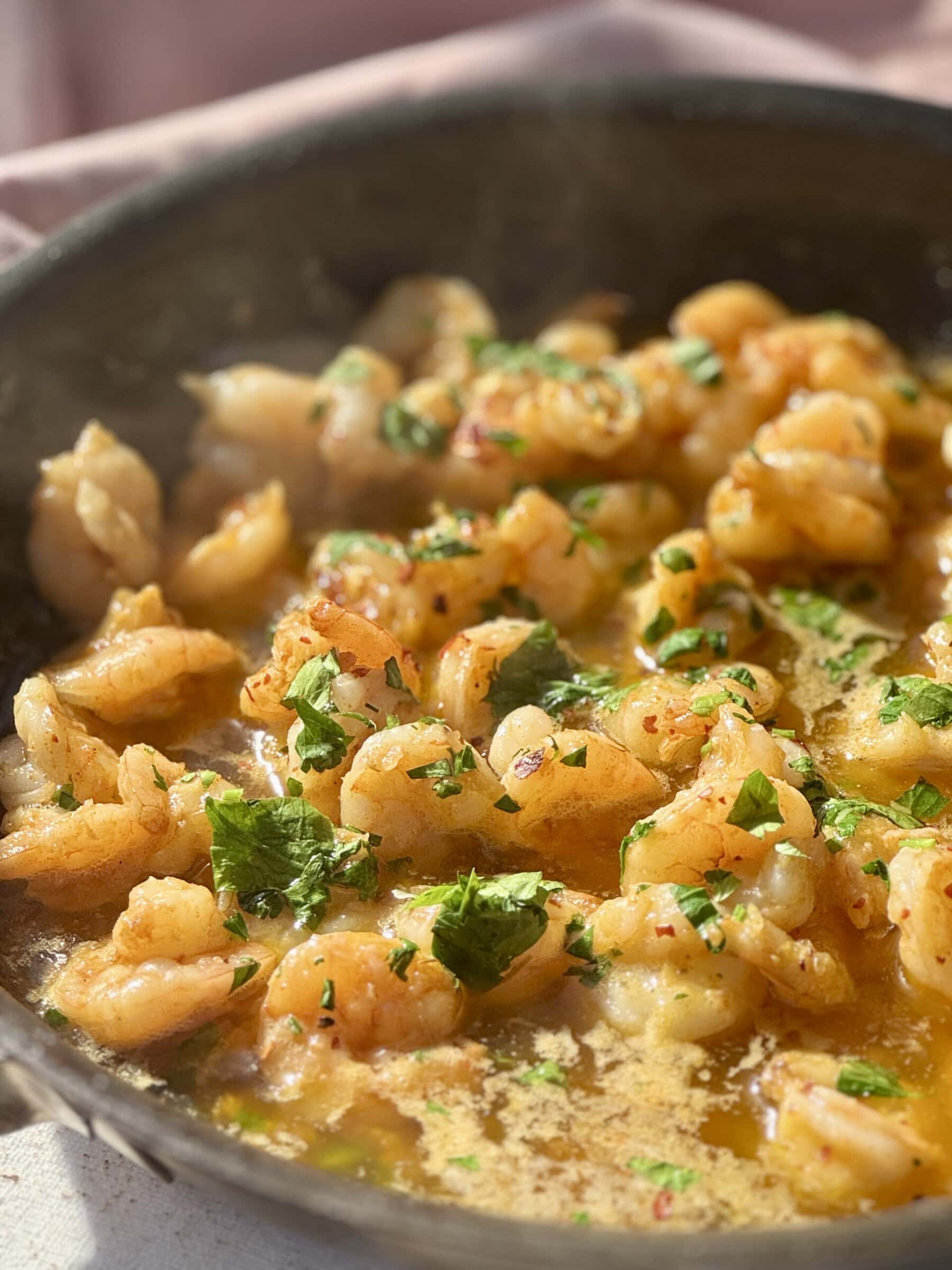 buttered garlic prawns in frying pan with parsley.