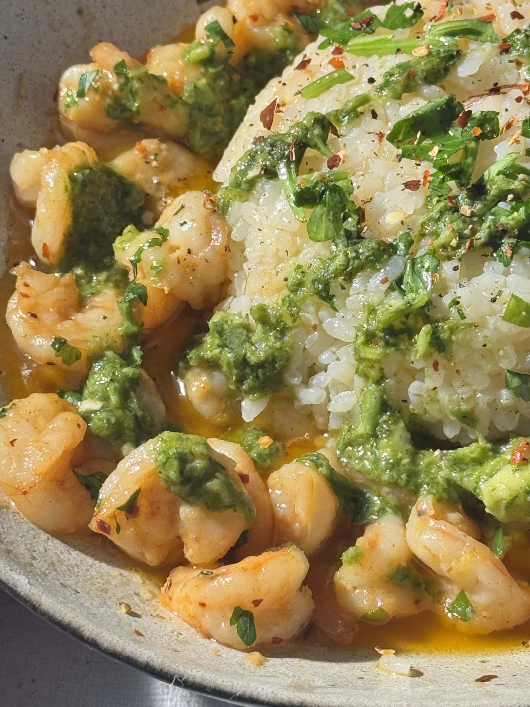 buttered garlic prawns with fluffy white rice and parsley in a grey bowl.