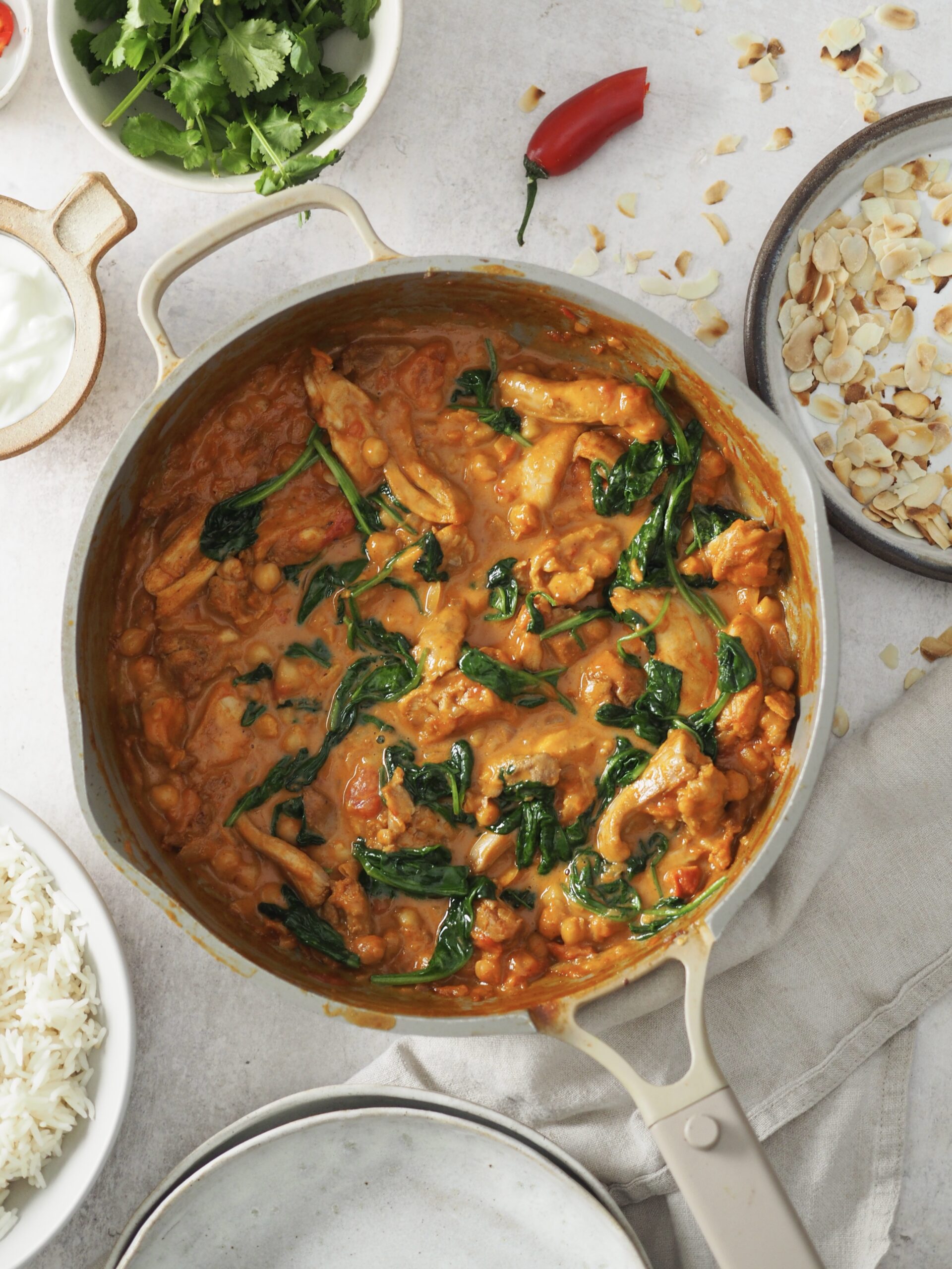 stirring spinach into the chicken and chickpea curry.