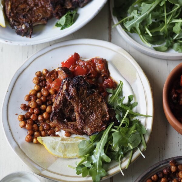 air fryer lamb chops with tomato aubergine stew and rocket on a white plate.