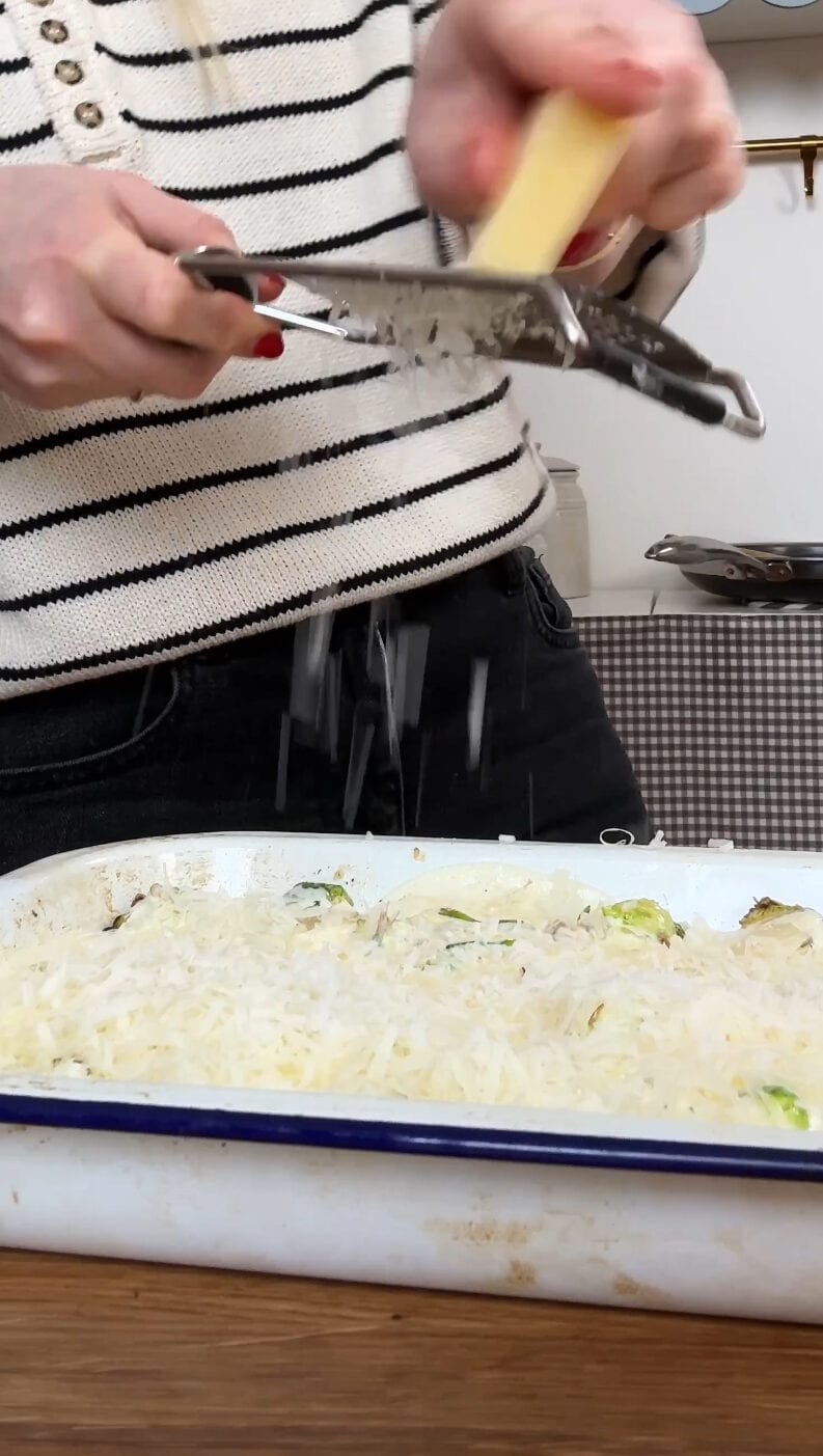 grating cheese over the brussels sprout casserole.