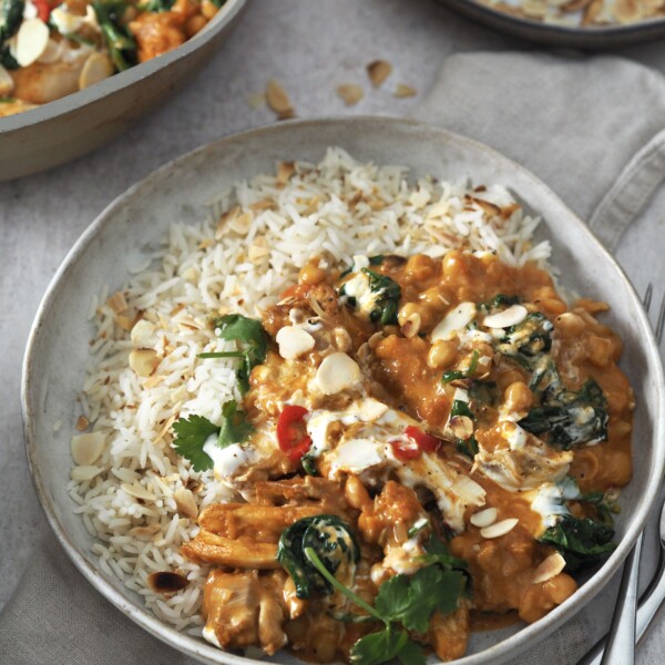 chicken and chickpea curry garnished with yoghurt and herbs served with rice.