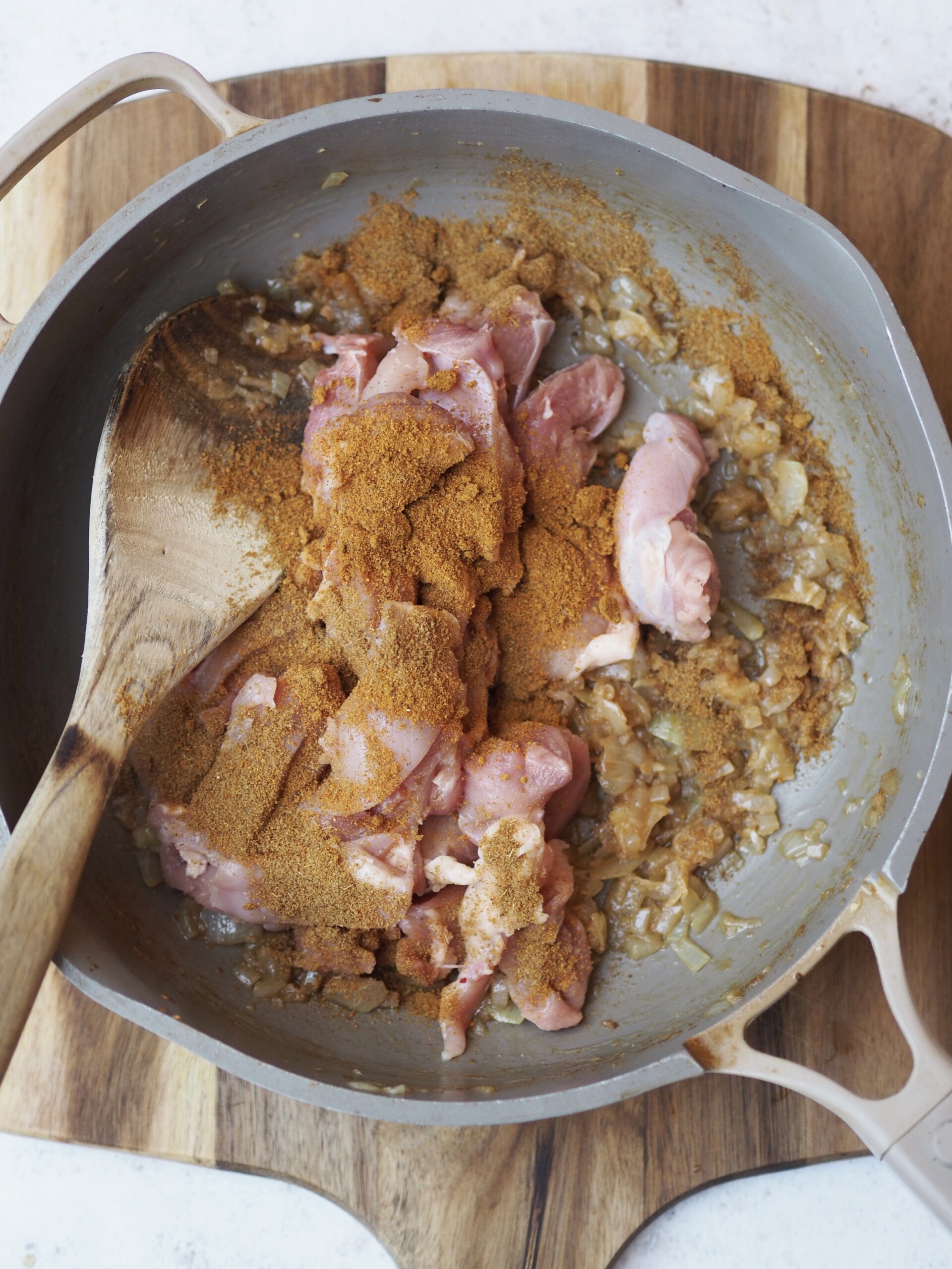 adding in spices and chicken to the curry.