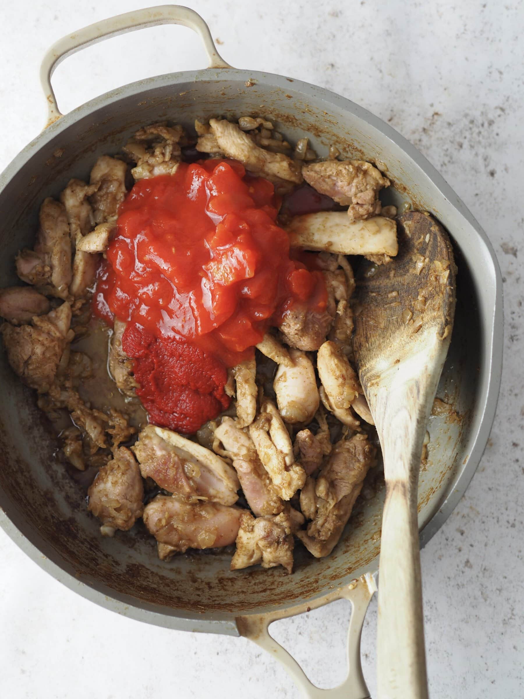 adding chopped tomatoes to the chicken.