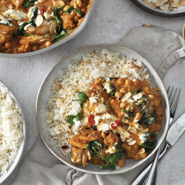 chicken and chickpea curry garnished with yoghurt and herbs served with rice.